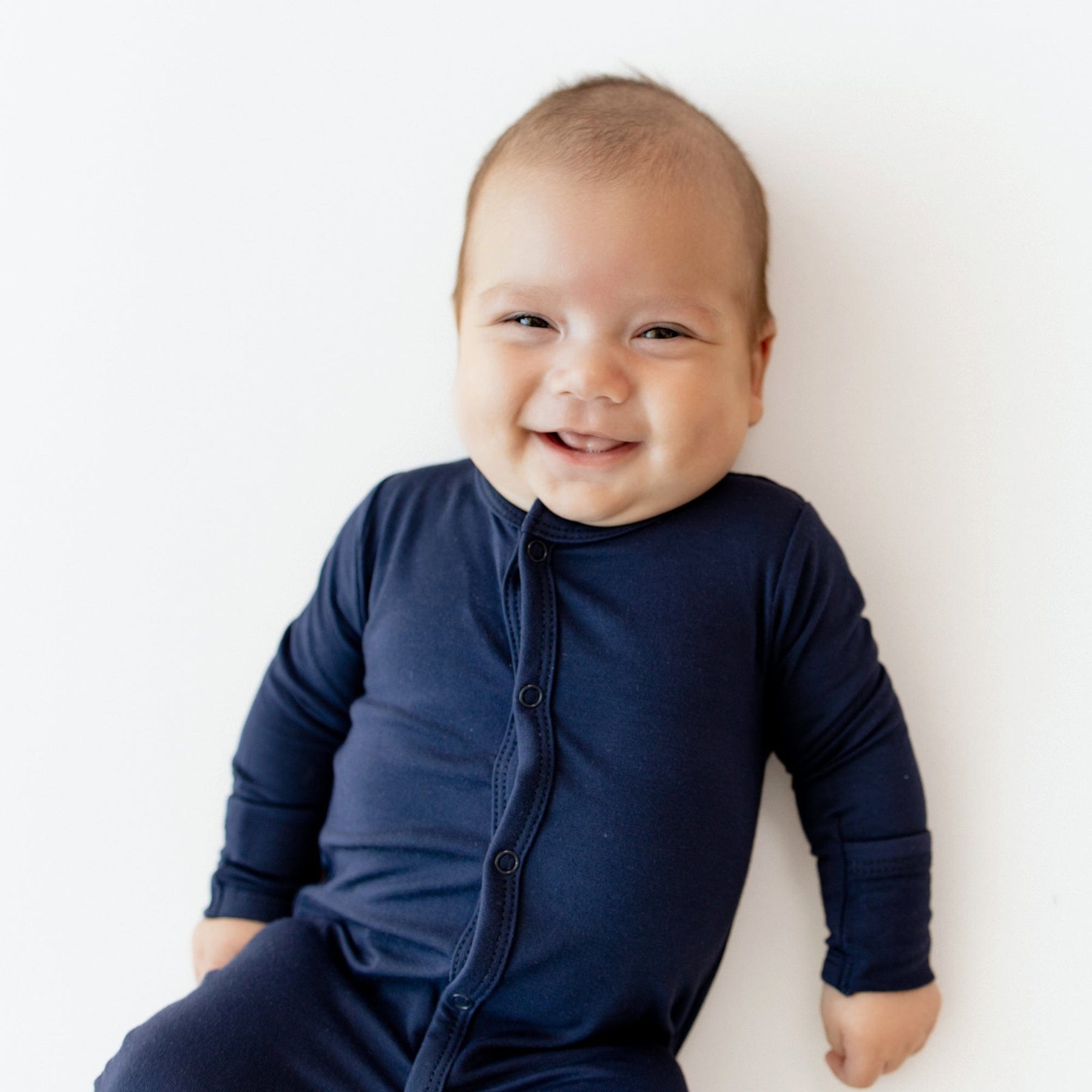 Infant wearing Kyte Baby Snap Footie pajamas in Navy