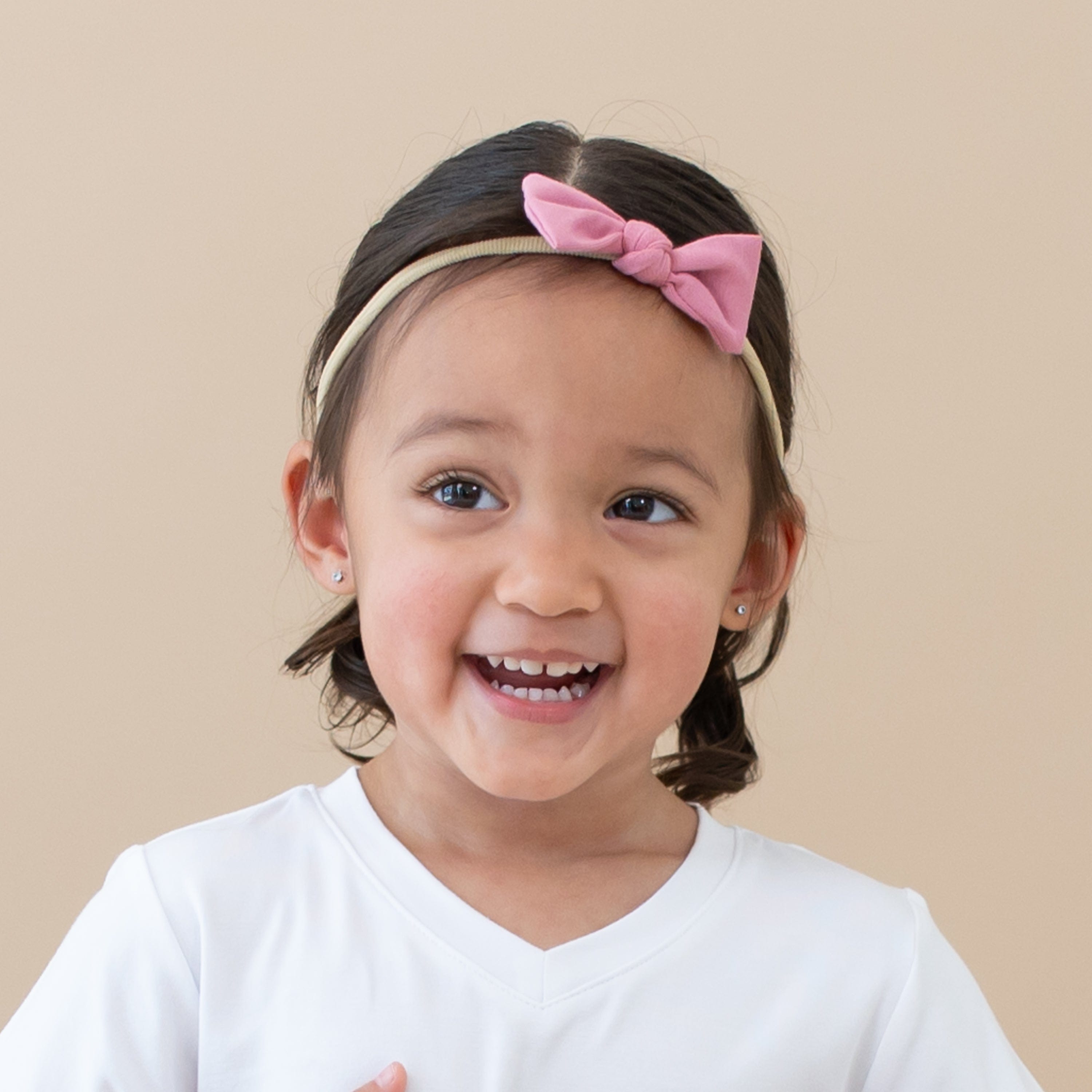 Toddler wearing Kyte Baby Tiny Nylon Bow in Apple Blossom