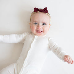 Infant wearing Kyte Baby Tiny Nylon Bow in Burgundy