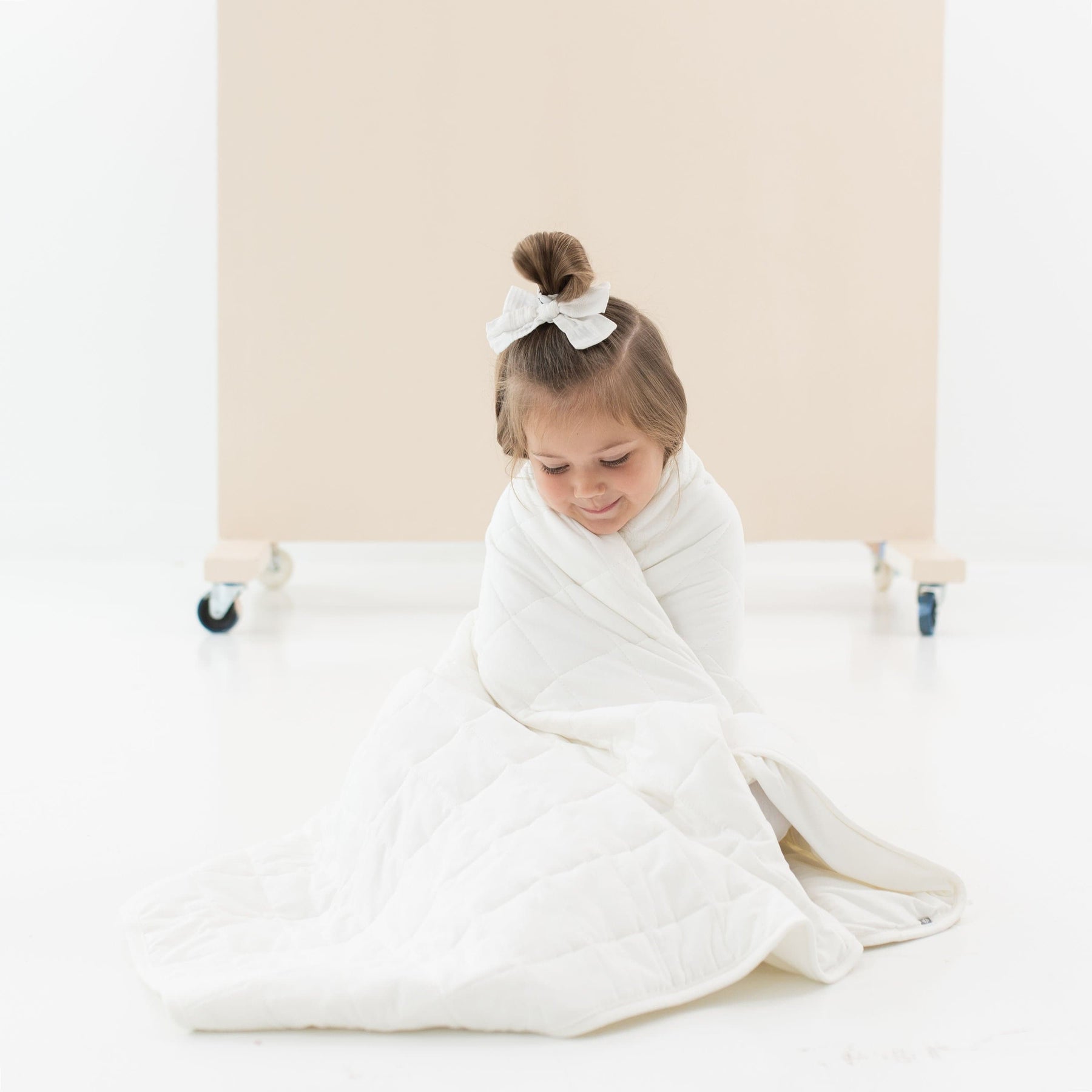 Child wrapped in Kyte Baby TOG 2.5 Toddler Blanket in Cloud white