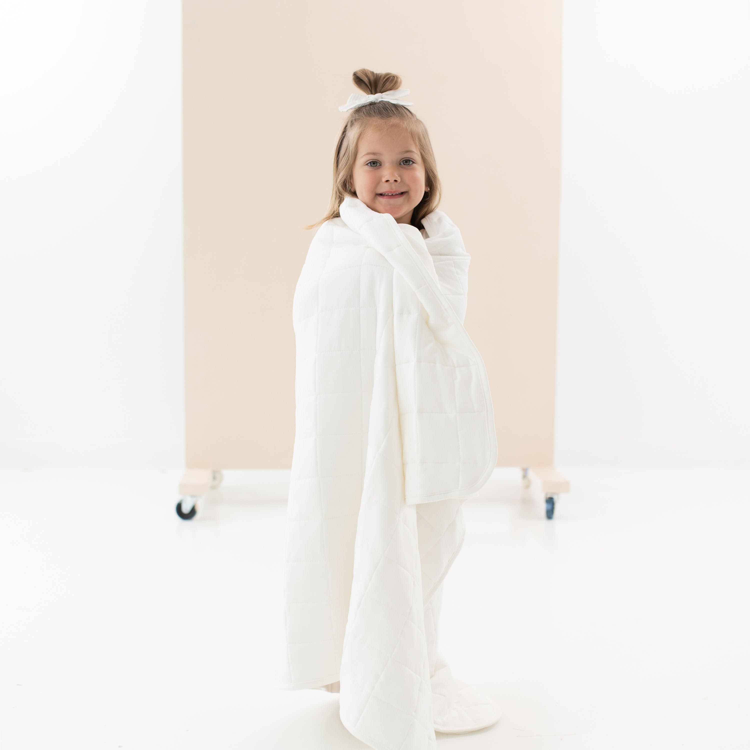 Child wrapped in Kyte Baby Toddler Blanket in Cloud 2.5