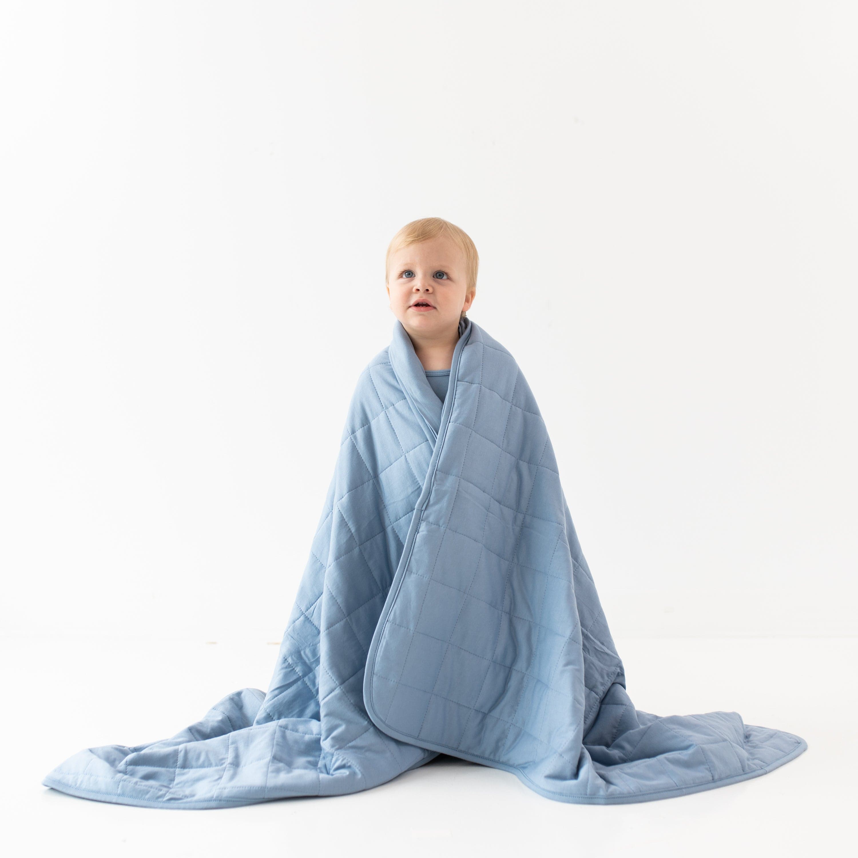 Child wrapped in Kyte Baby Toddler Blanket in Slate 2.5