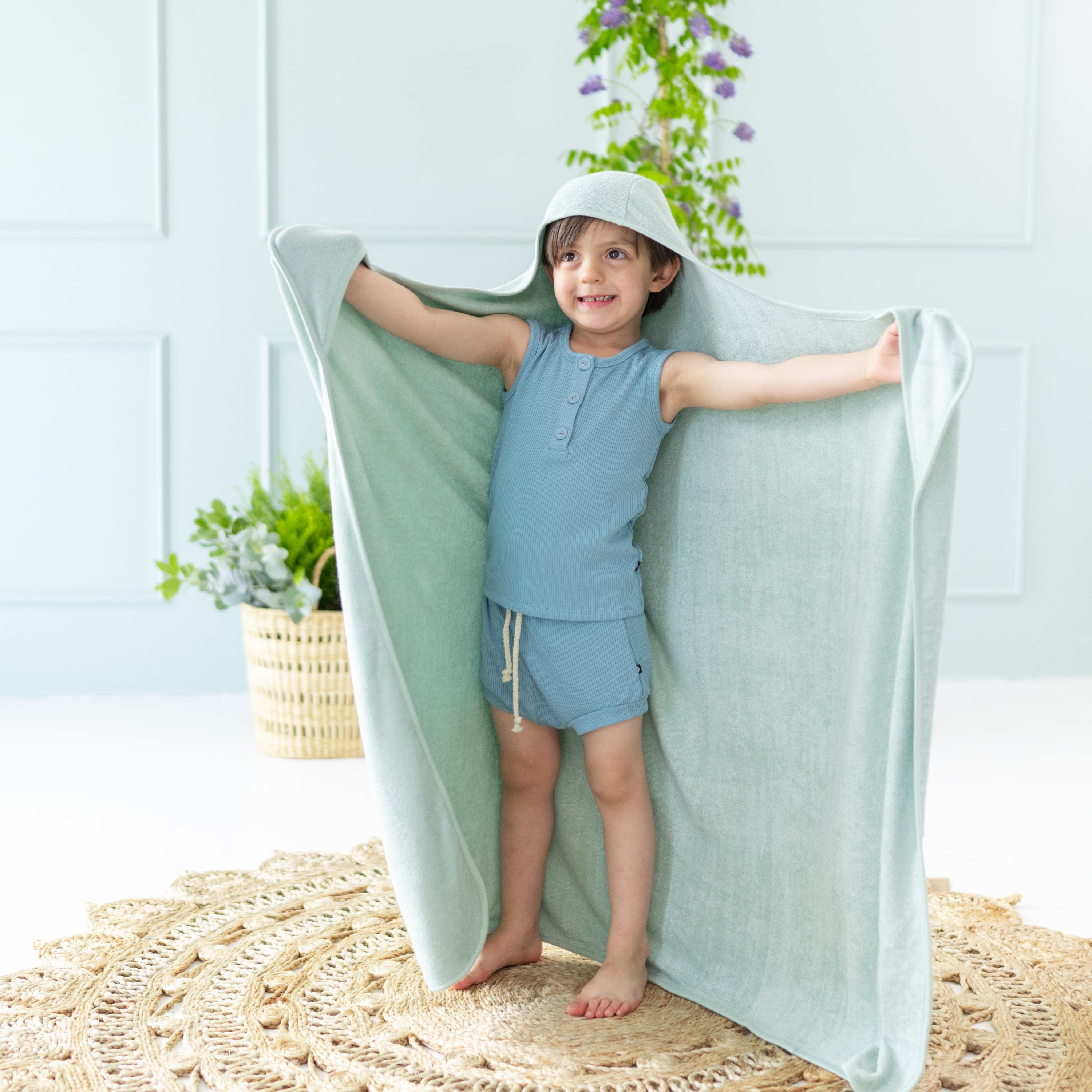 Toddler wrapped in Kyte Baby Hooded Bath Towel in Sage