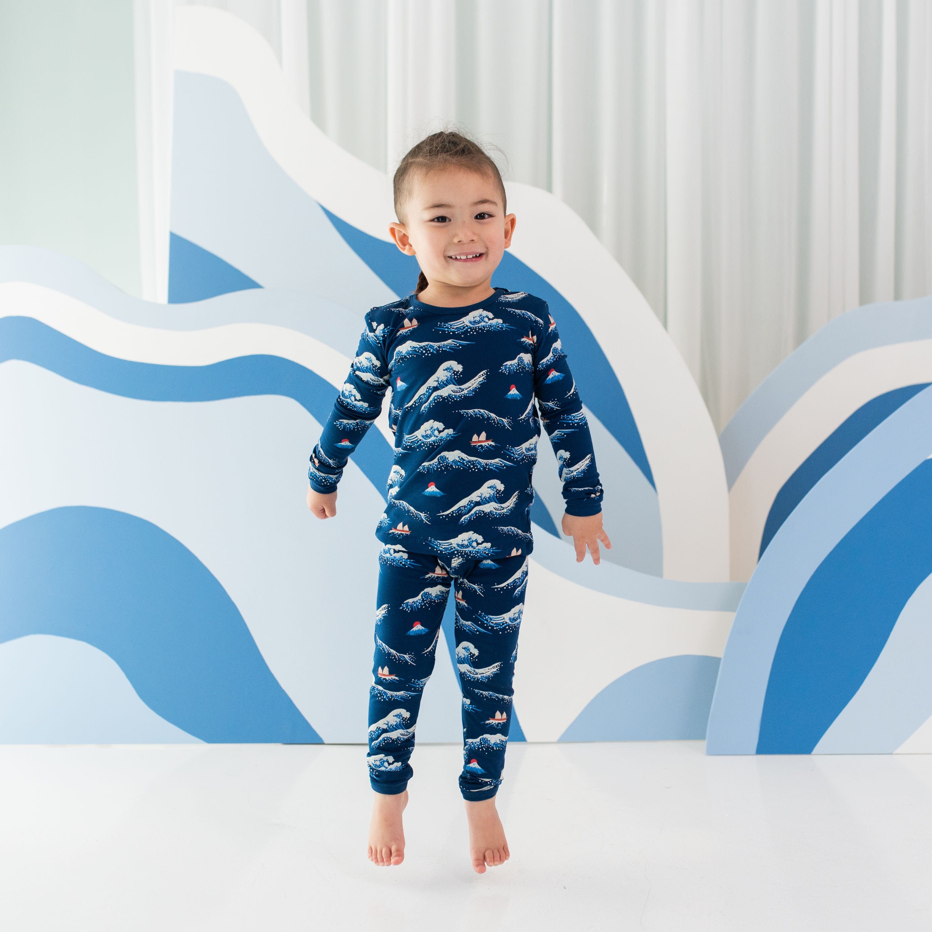 Child wearing Kyte Baby Long Sleeve Pajamas in Wave