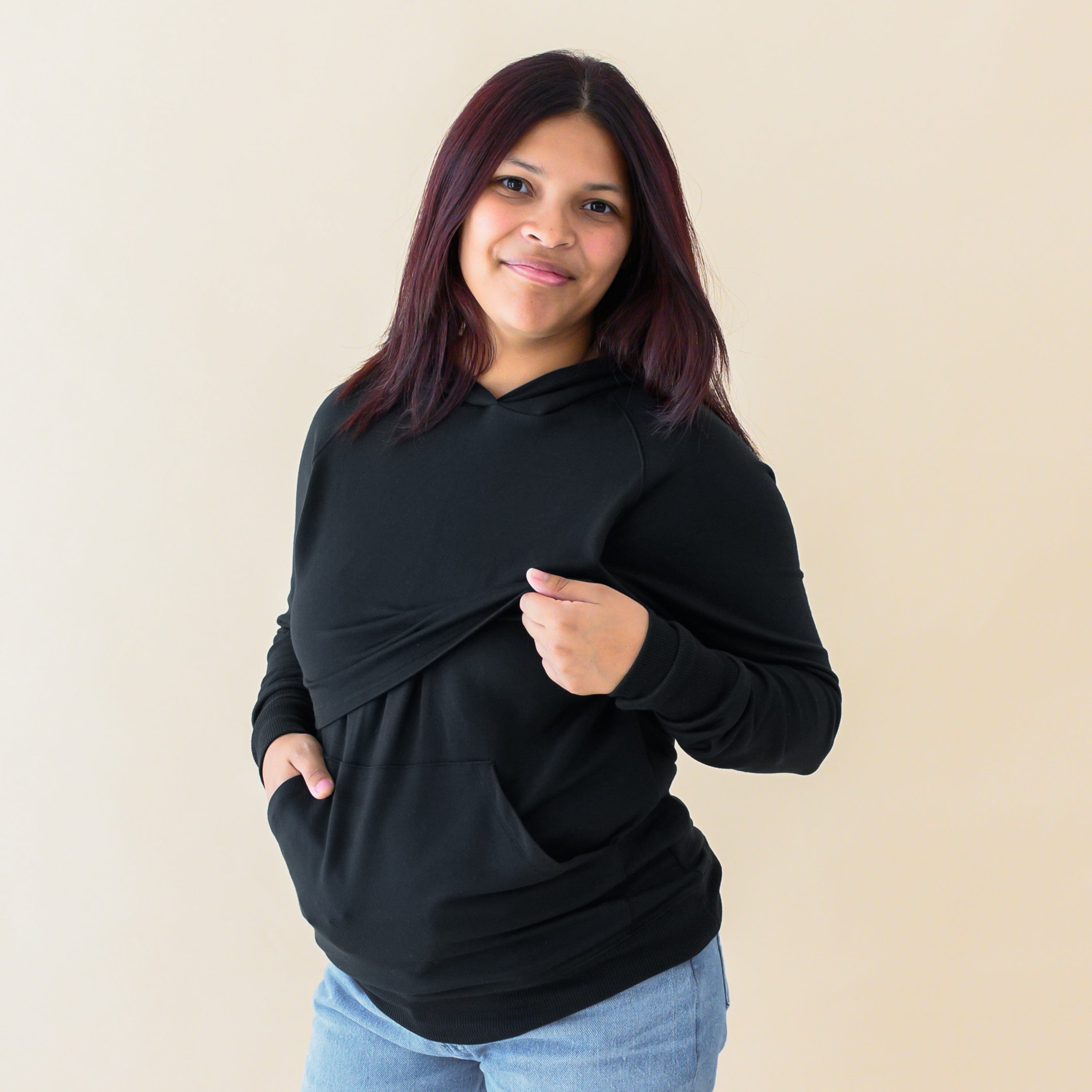 Woman demonstrating function of Kyte Baby Women's French Terry Nursing Hoodie in Midnight