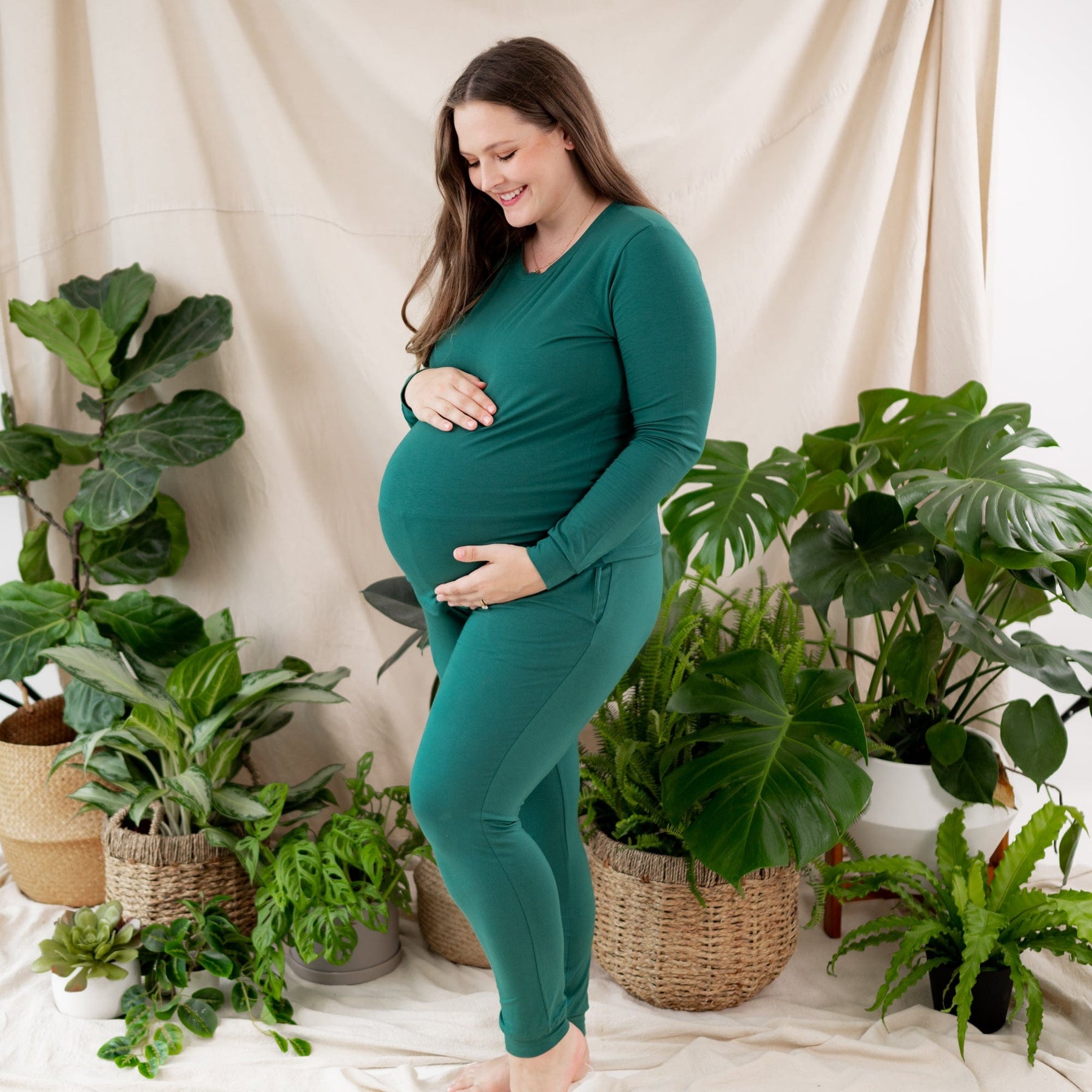 Woman wearing Kyte Baby women's jogger pregnancy pajama set in Emerald