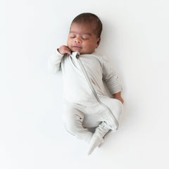 Sleeping infant wearing the Zippered Footie in Oat