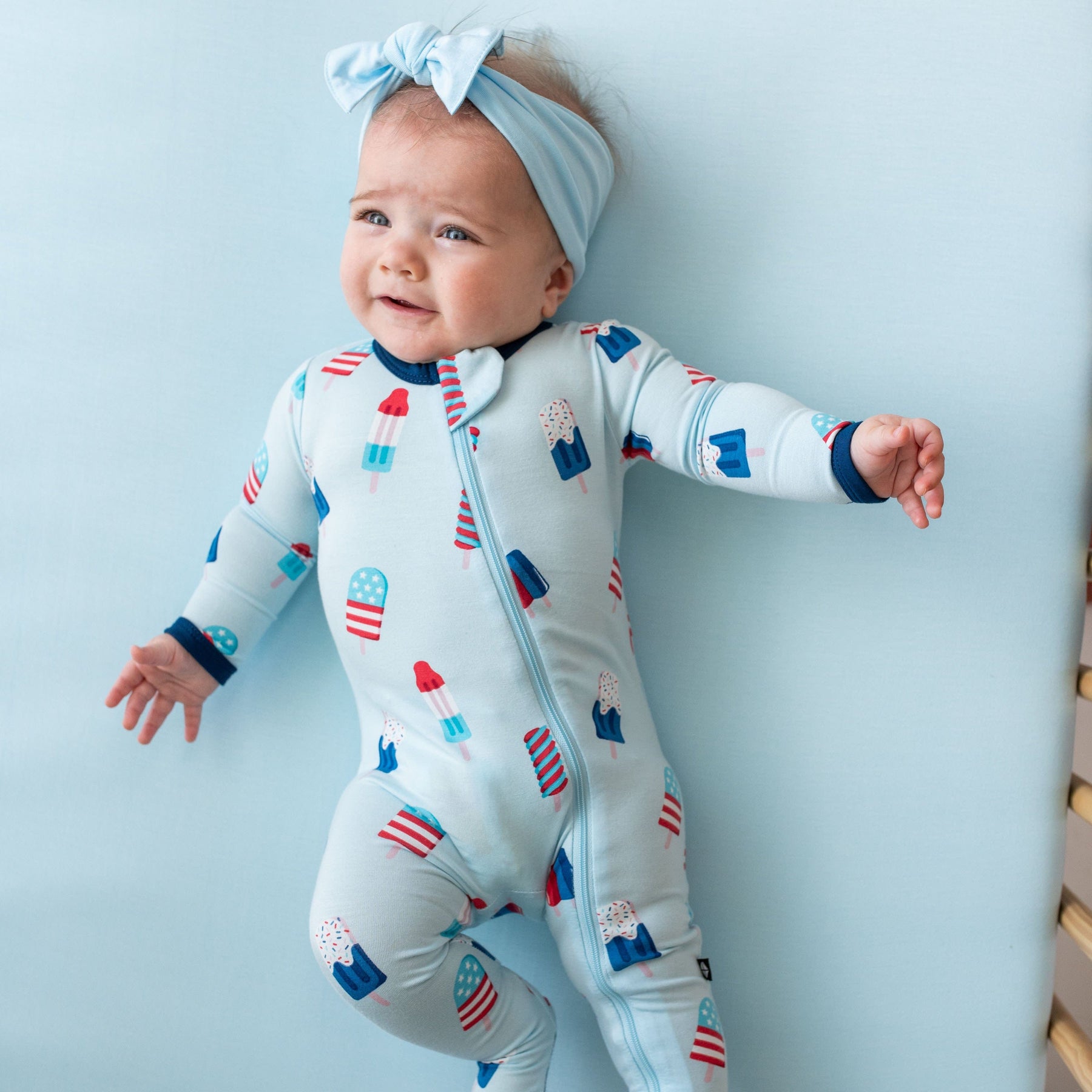 Infant wearing Kyte Baby Zippered Footie in Popsicle