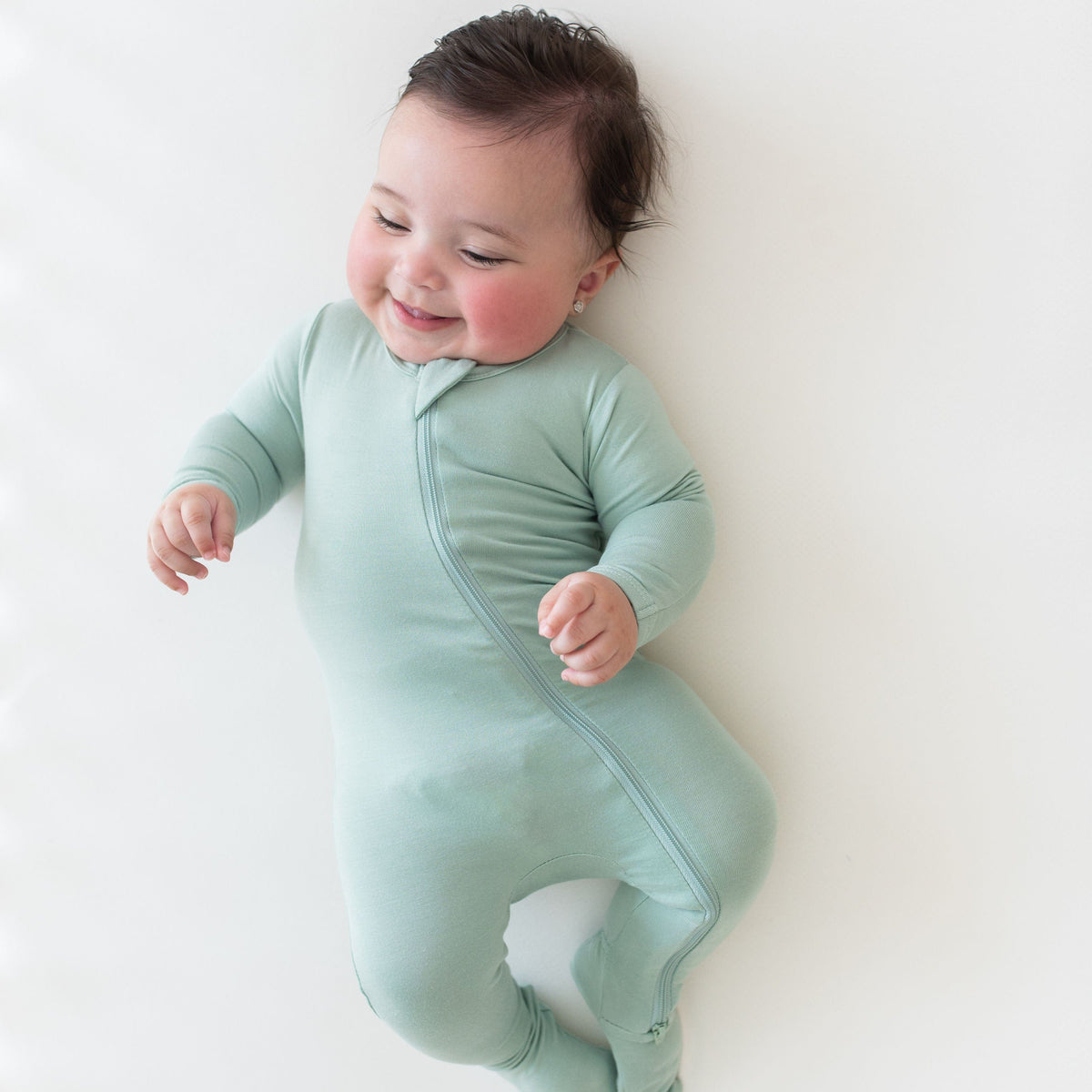Baby wearing Kyte Baby Zippered Footie in Sage