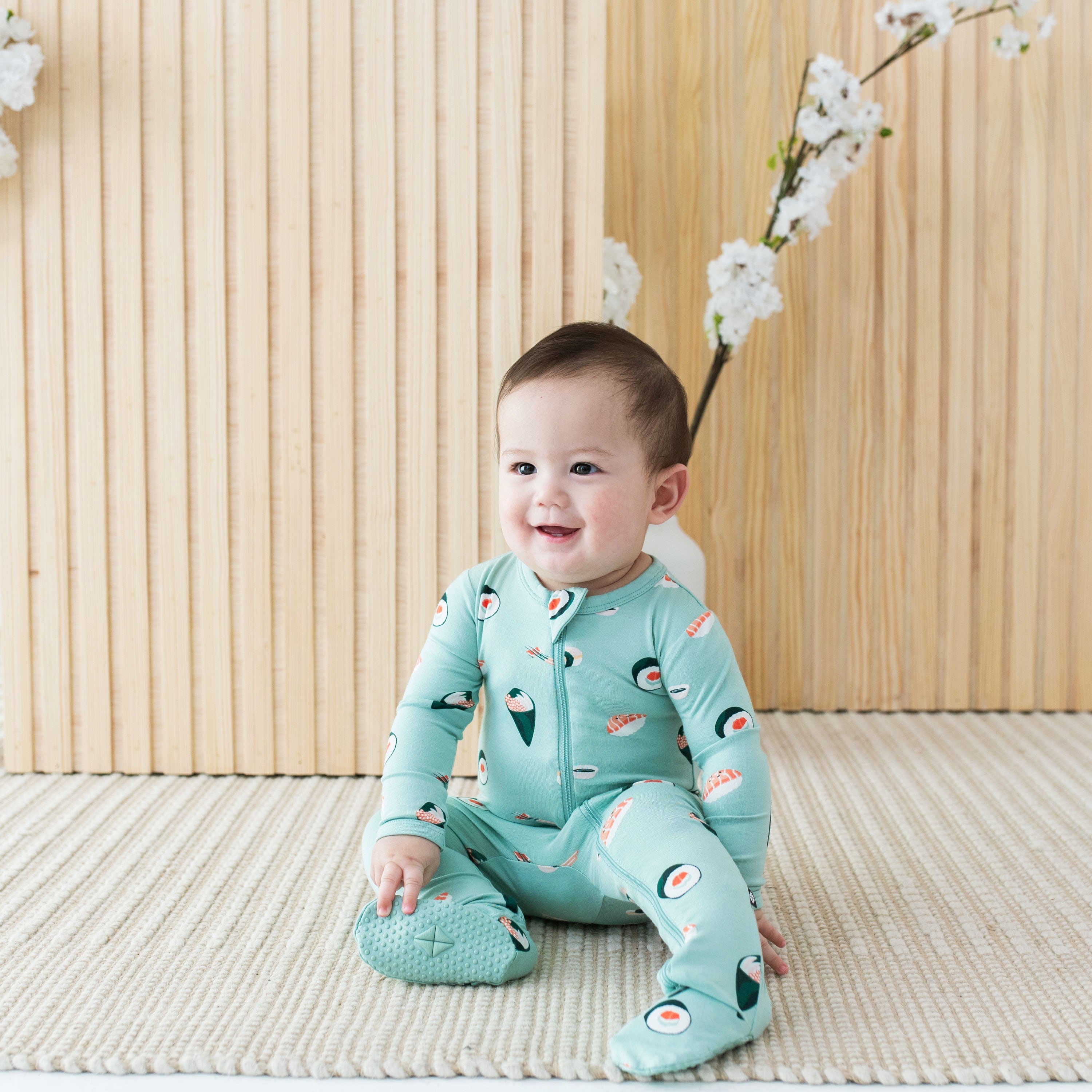 Baby wearing Kyte Baby bamboo Zippered Footie pajamas in  Sushi