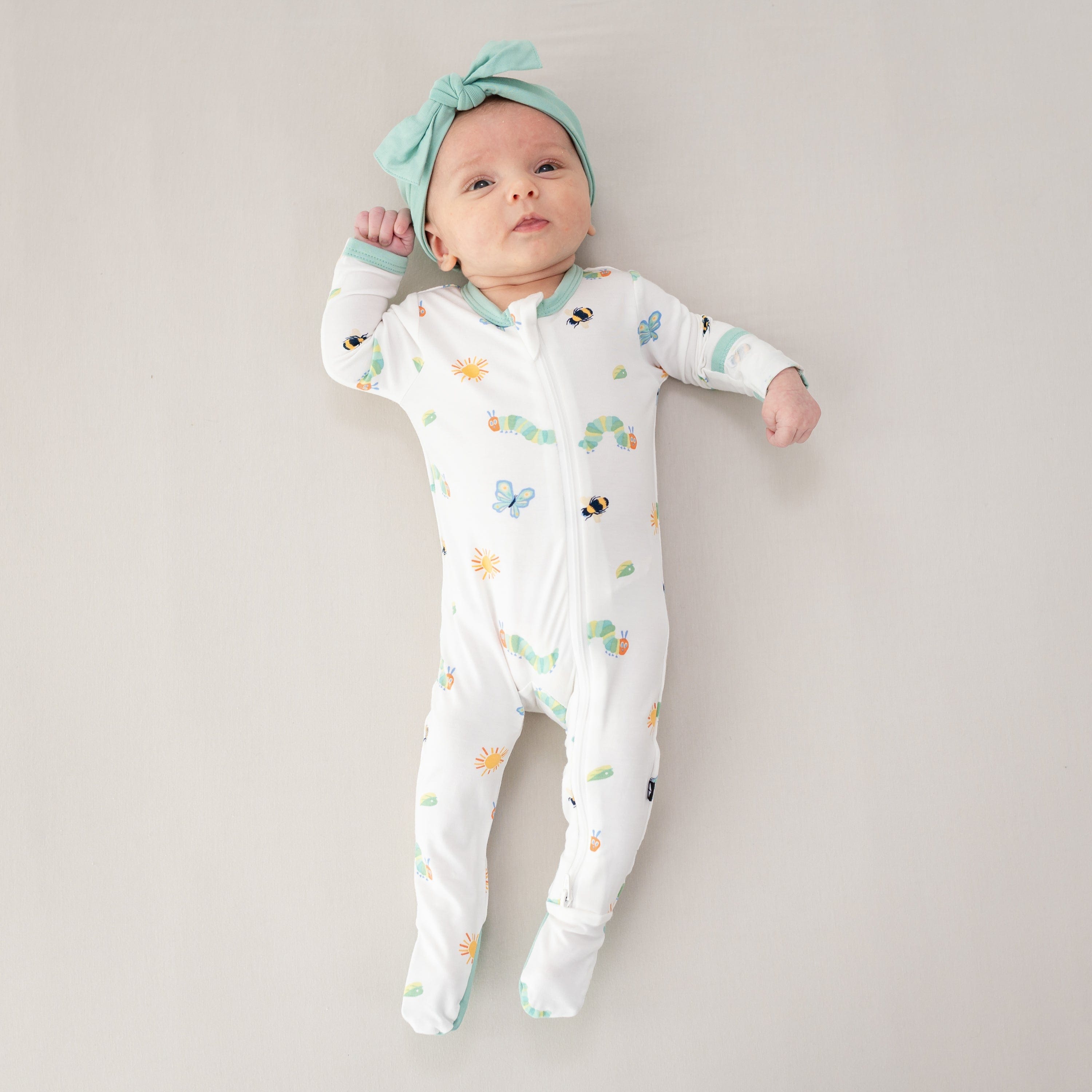 Infant model wearing the Zippered Footie in The Very Hungry Caterpillar™ and Friends with Wasabi Knotted Bow