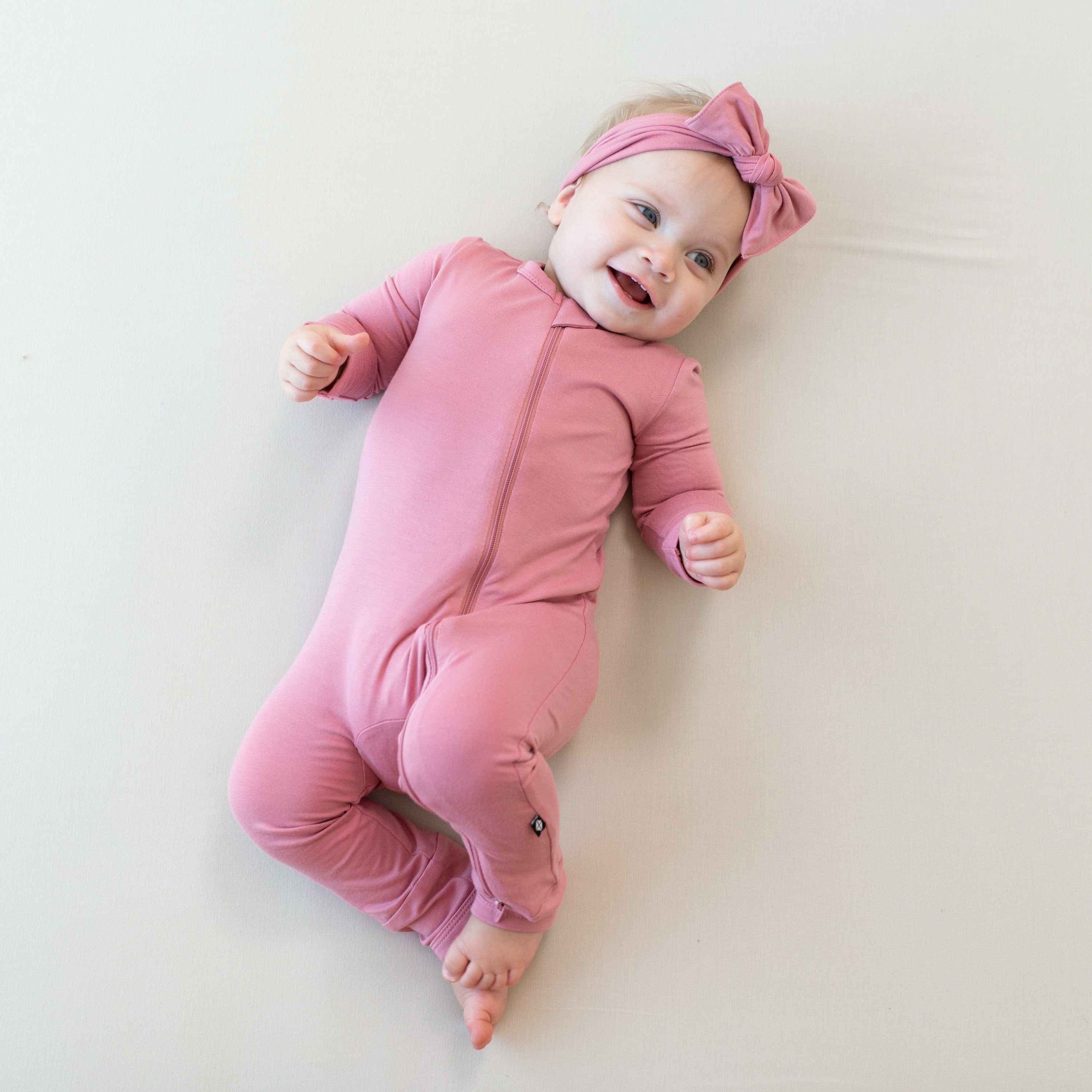 Infant wearing Zippered Romper in Apple Blossom with matching bow headband