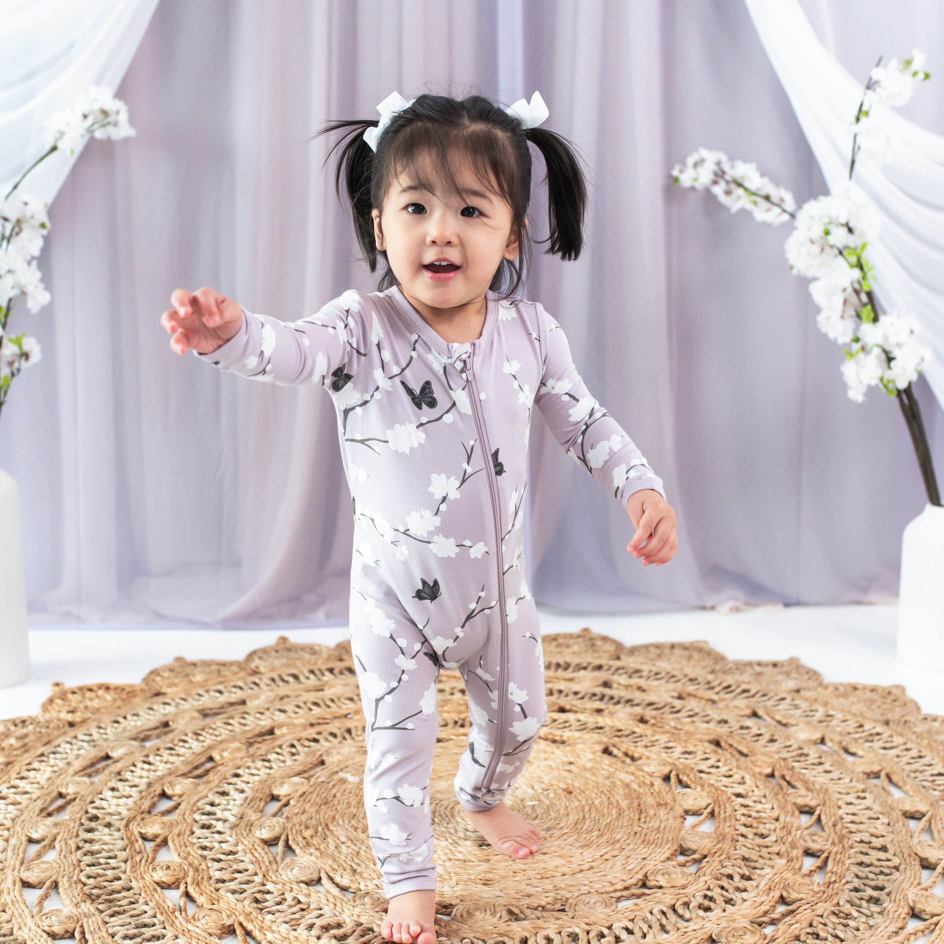 Toddler wearing Kyte Baby Zippered Romper in Cherry Blossom