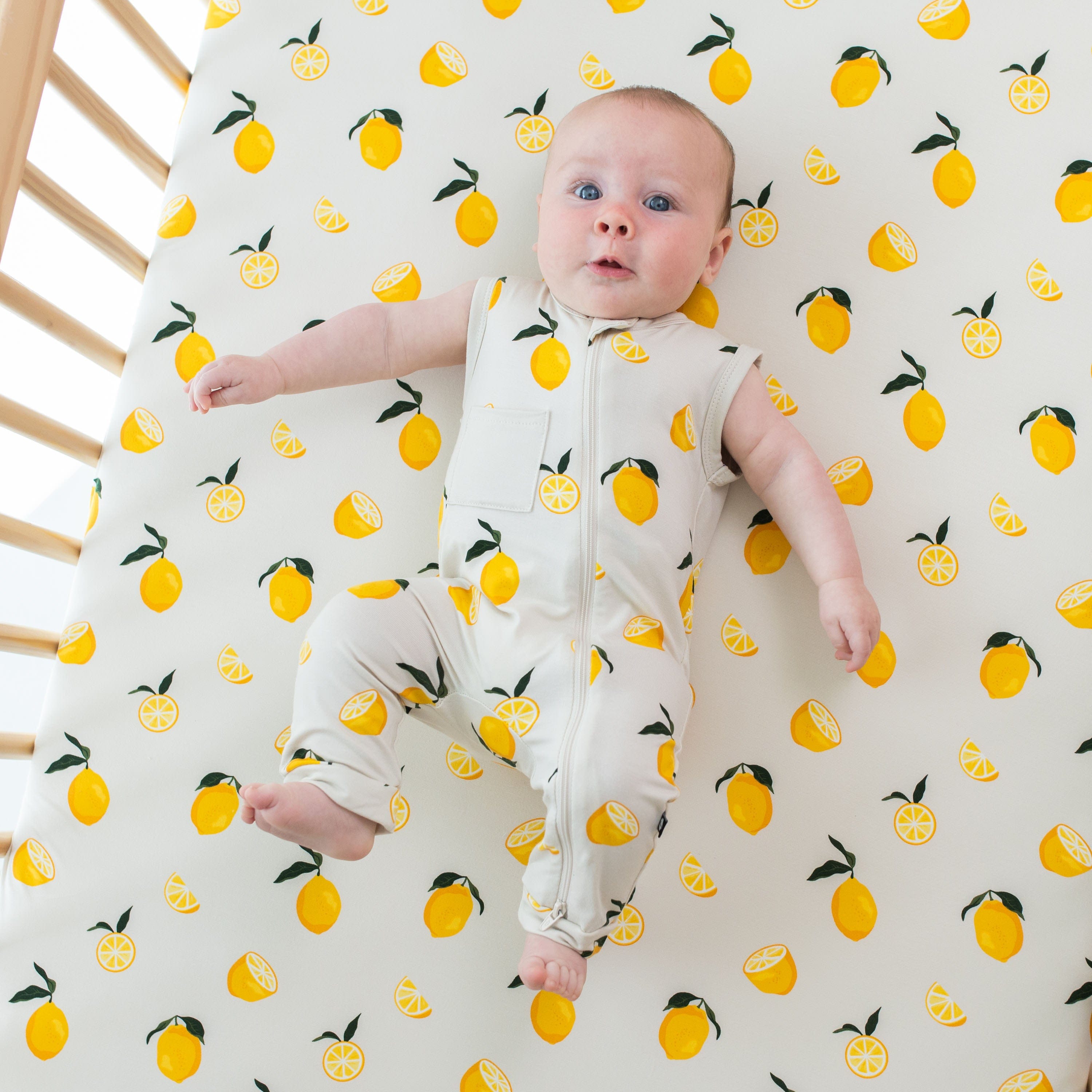 Baby wearing Kyte Baby bamboo Zippered Sleeveless Romper in Lemon