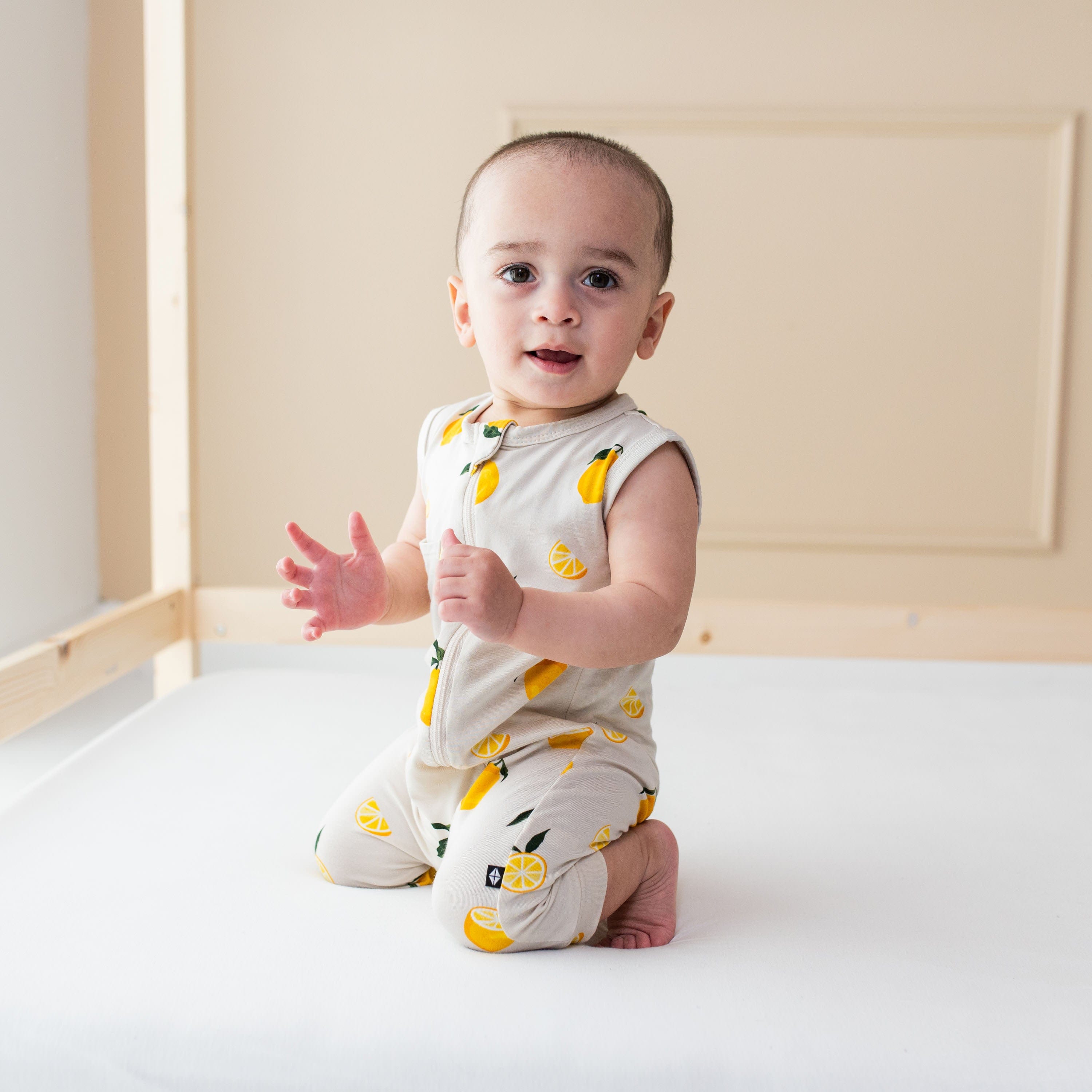 Infant wearing bamboo Kyte Baby Zippered Sleeveless Romper in Lemon pattern