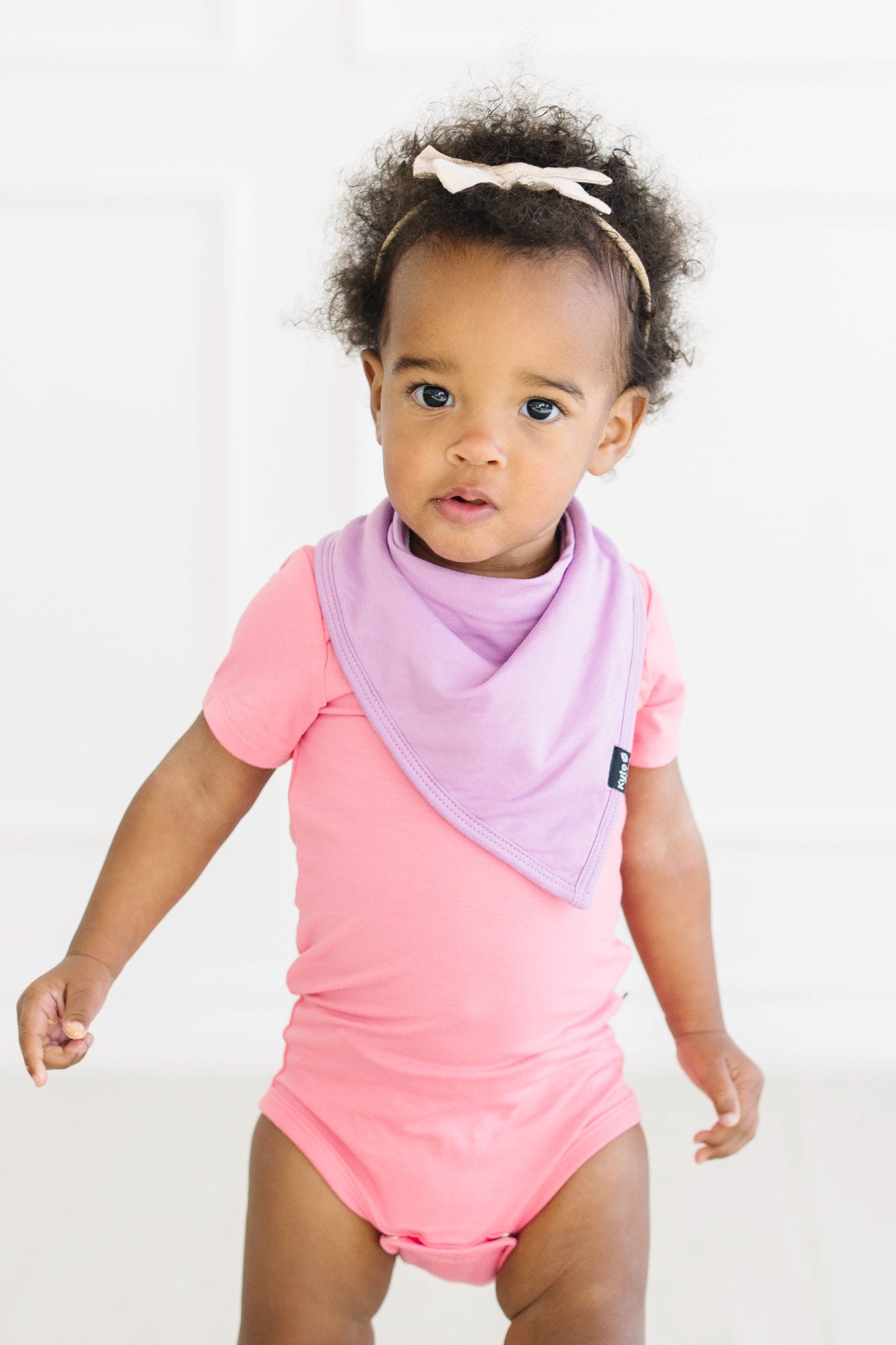 toddler wearing short sleeve bodysuit in guava and poi bib
