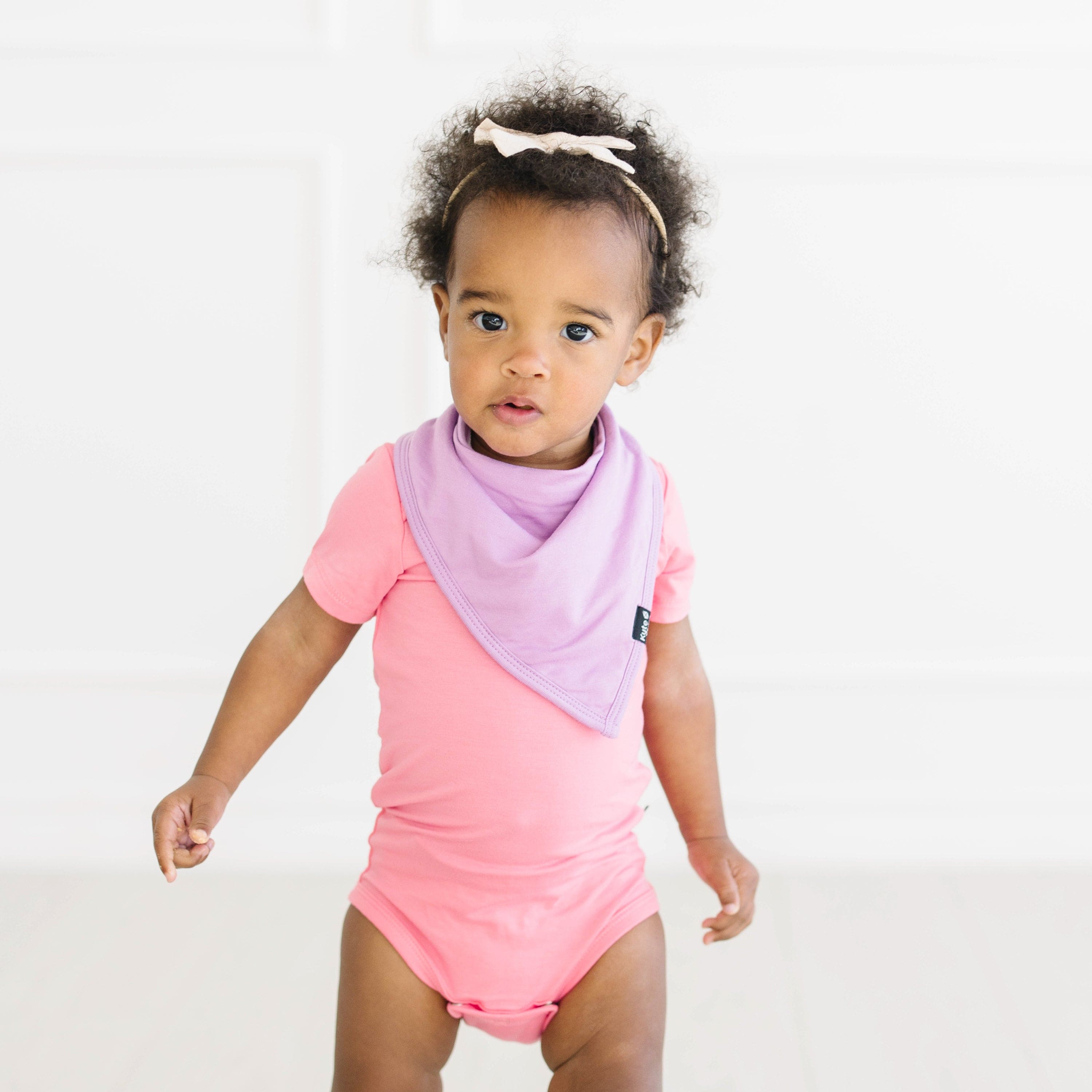 toddler wearing short sleeve bodysuit in guava and poi bib