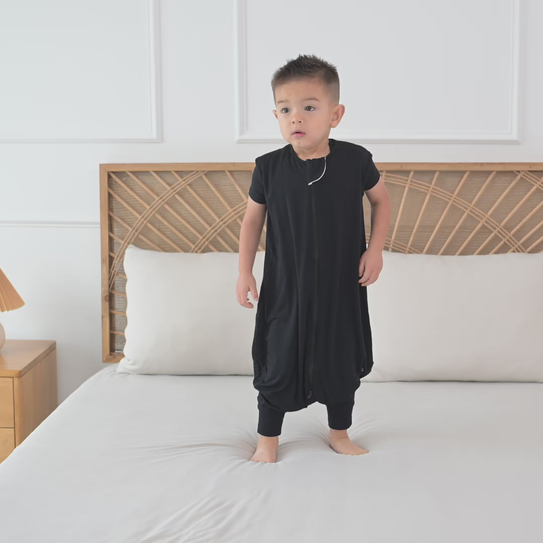 Video of child model standing on a bed wearing the Sleep Bag Walker in Midnight 0.5