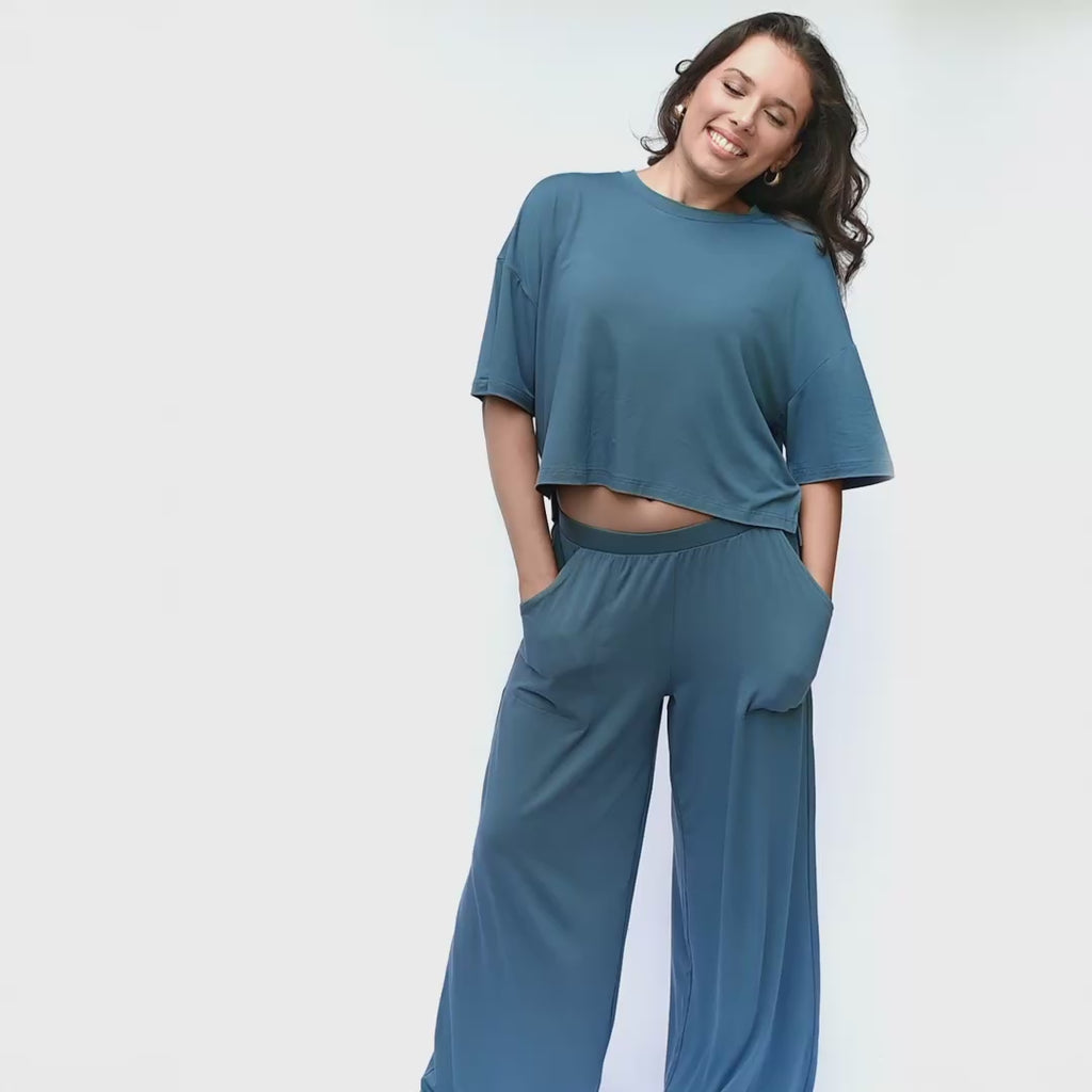 woman modeling a wide leg pant set in a blue color in a white studio setting