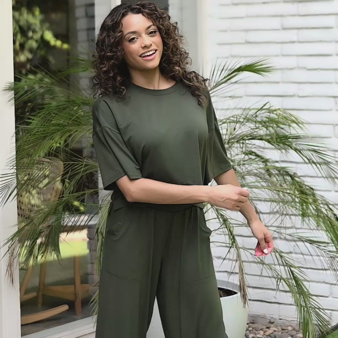 woman modeling matching wide let pant set in a deep green color in an outdoor home setting