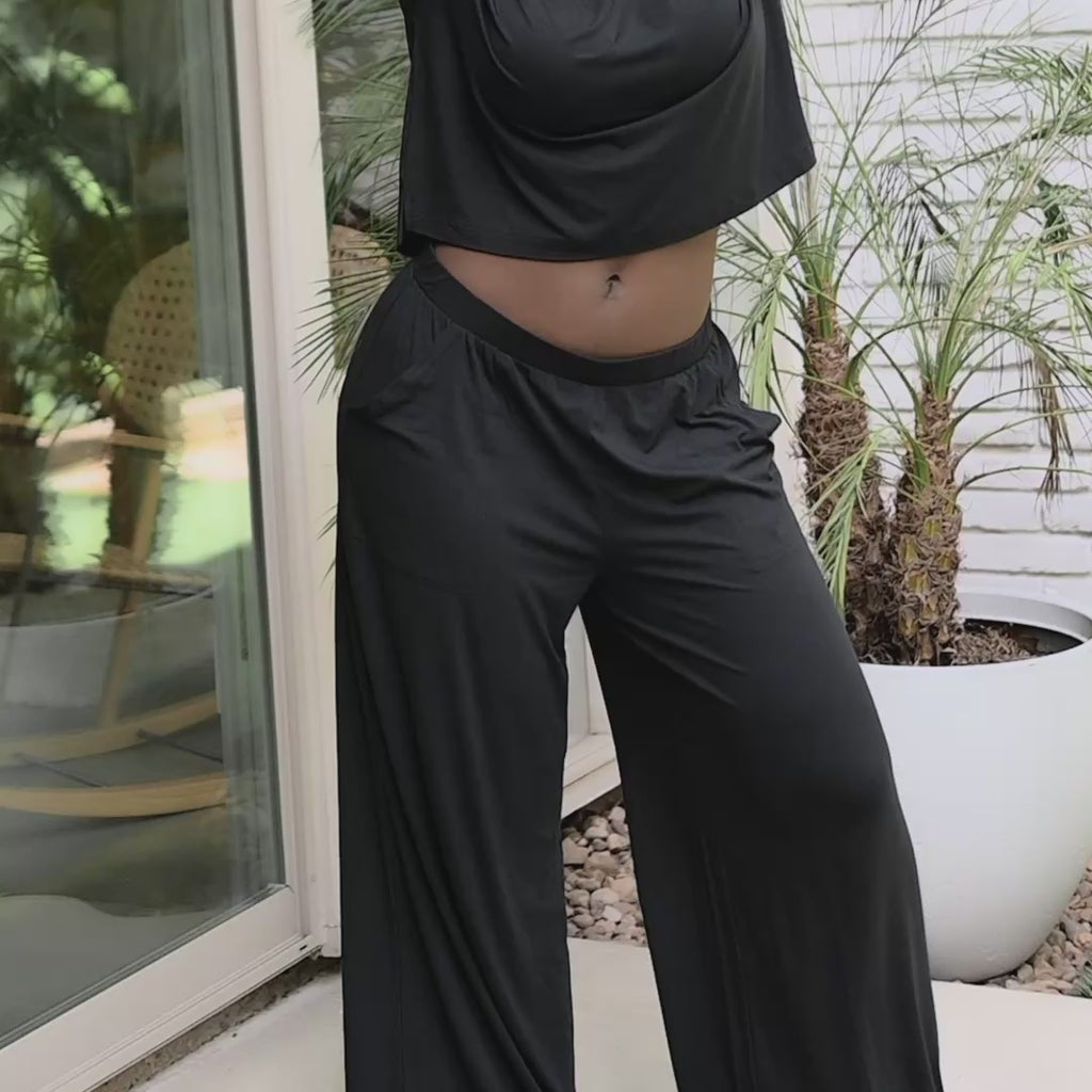 woman modeling wide leg pant set in a black color with a home setting in the background 