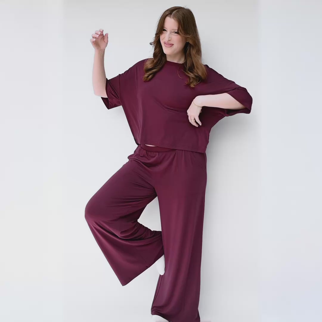 woman modeling burgundy wide leg pant set with a white studio backdrop