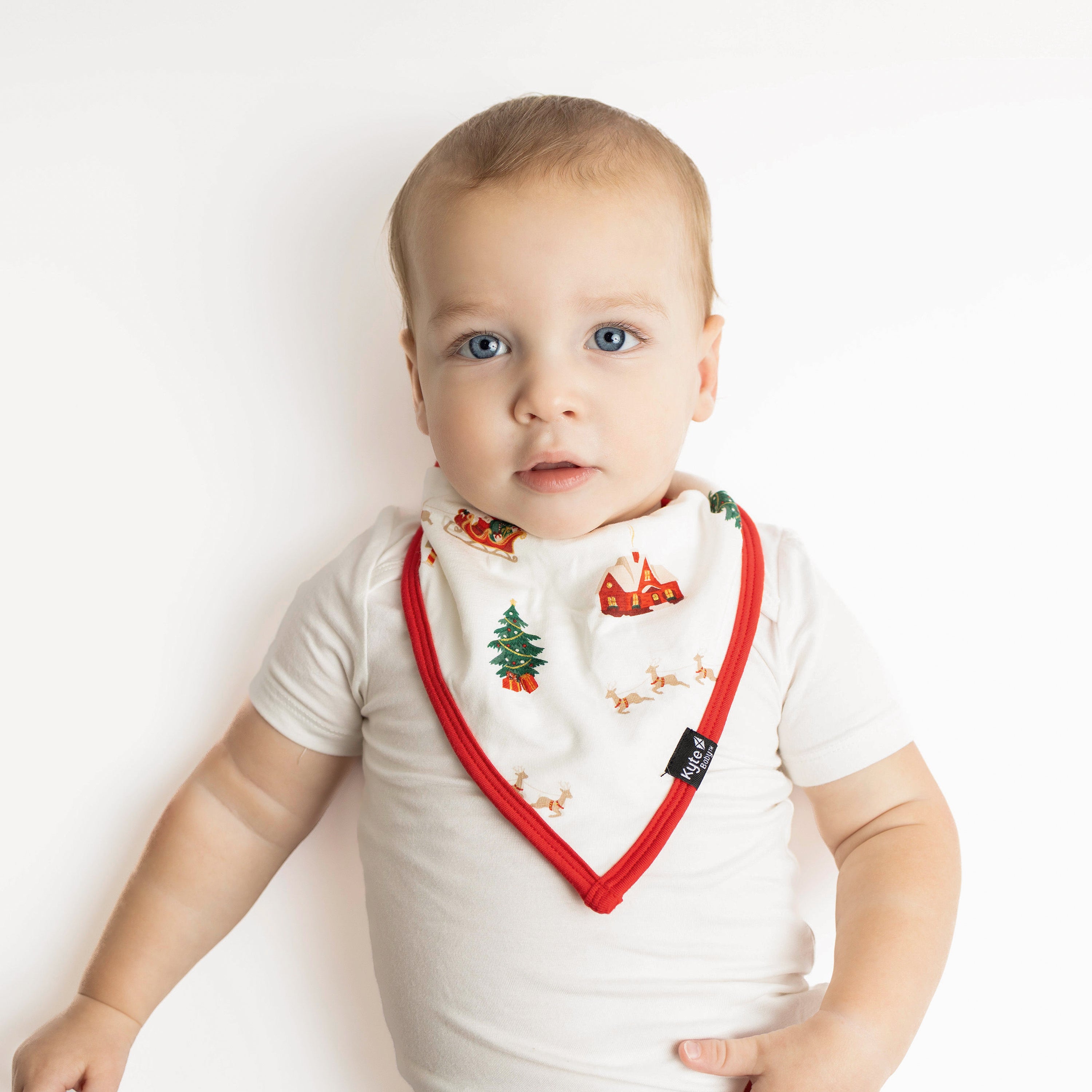 Young toddler laying down wearing the Bib in Santa Sleigh