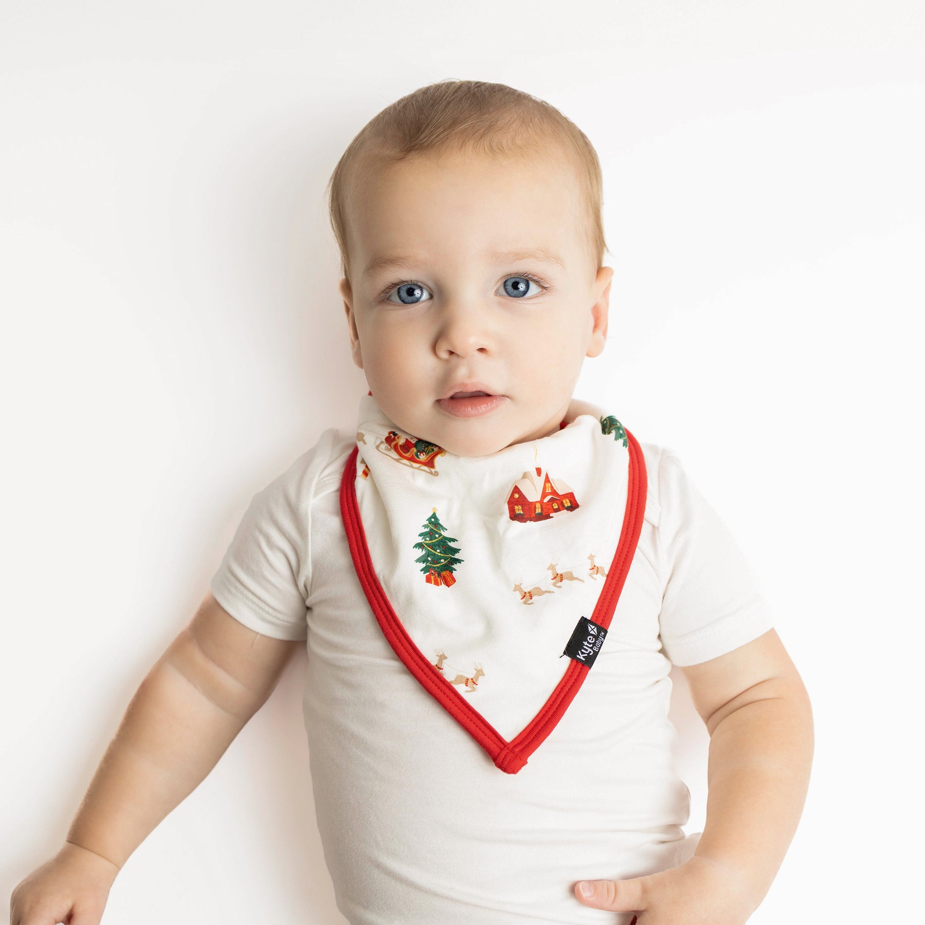 Young toddler laying down wearing the Bib in Santa Sleigh
