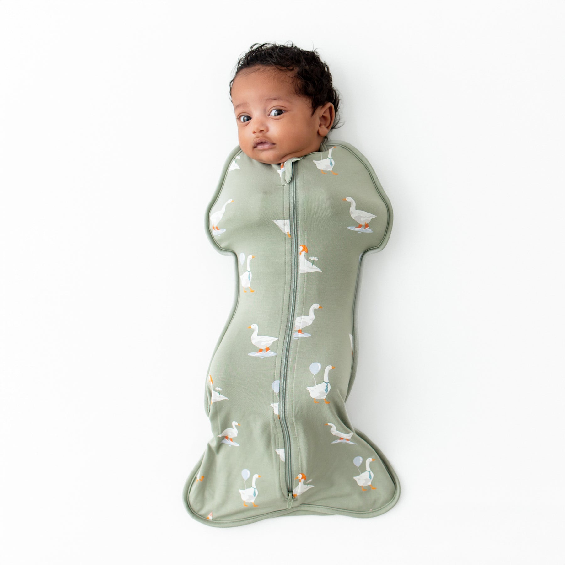 Infant laying down wearing the Swaddle Bag in Silly Goose 0.5