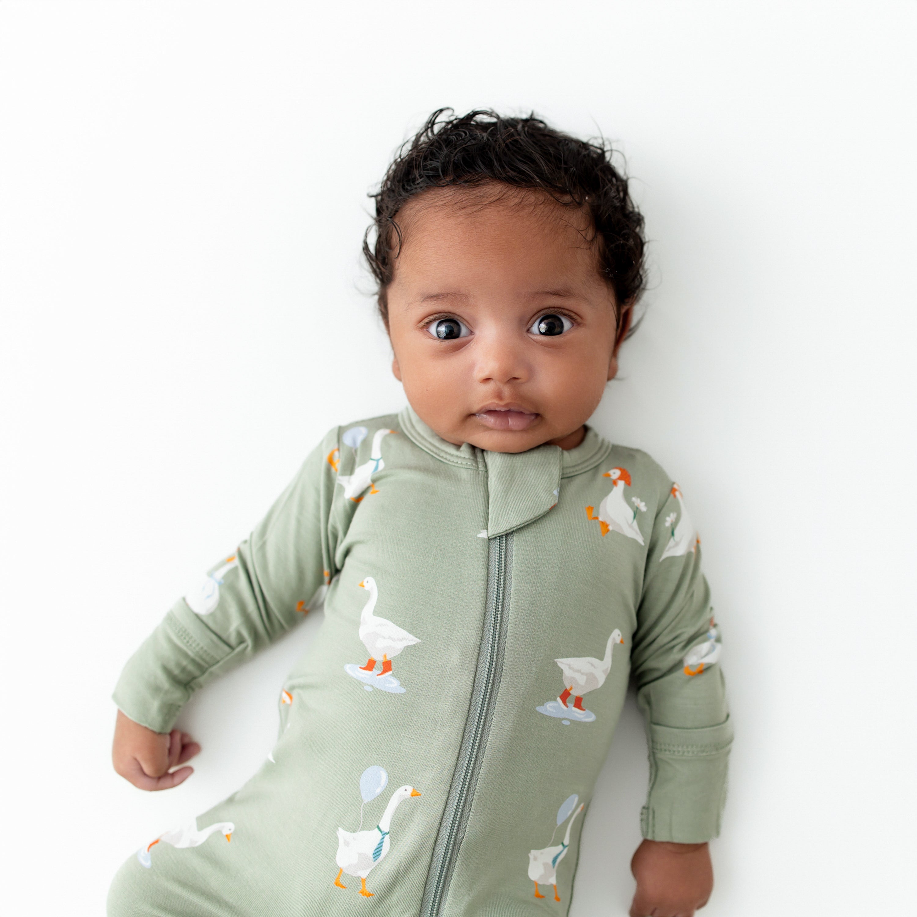 baby wearing green zippered footie in a silly goose pattern