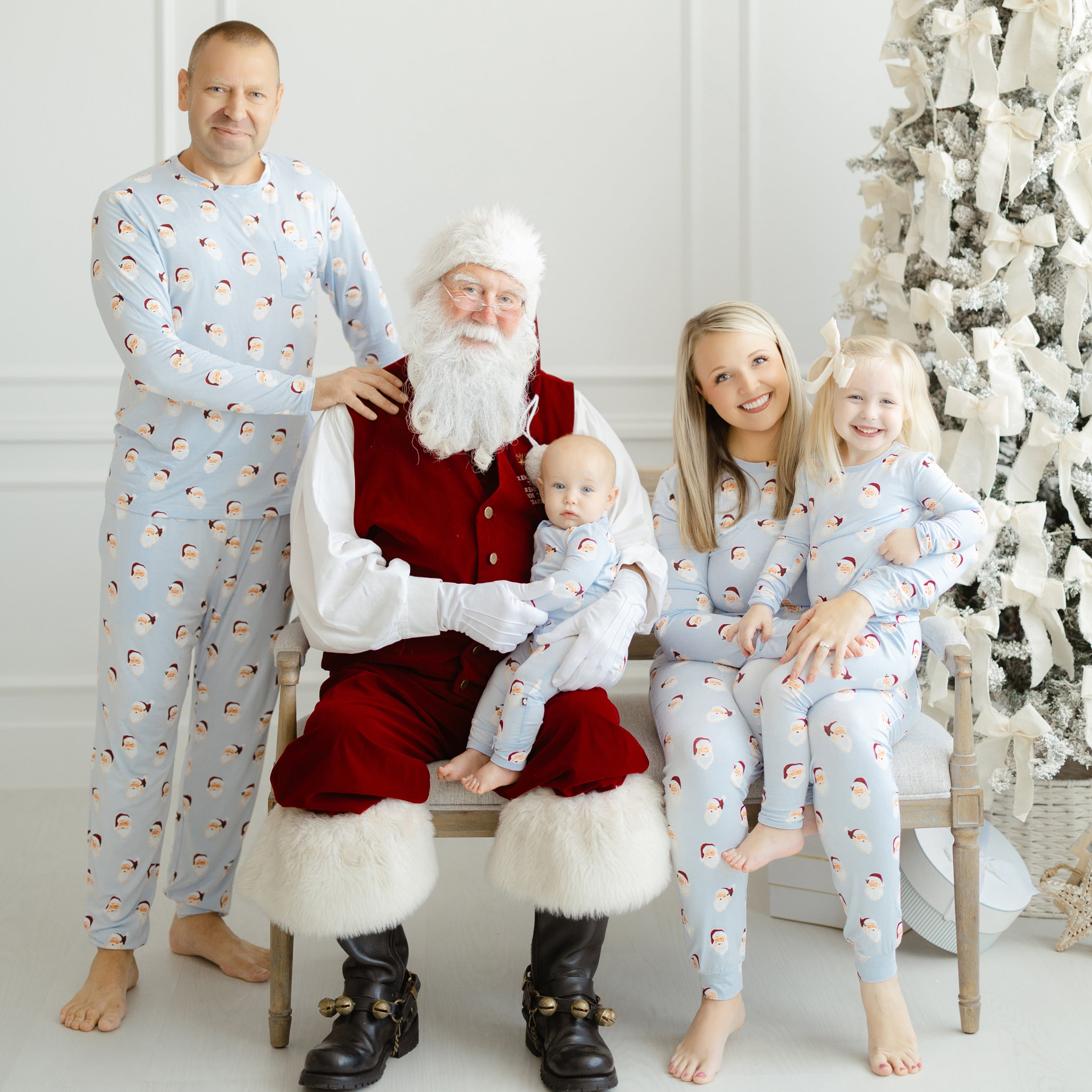 Family of four matching in Vintage Santa sitting on a bench with a Santa Clause holding their toddler