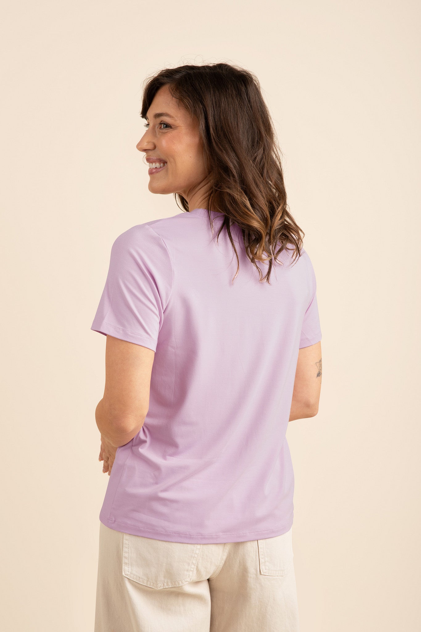 Woman wearing a light purple t-shirt against a beige background