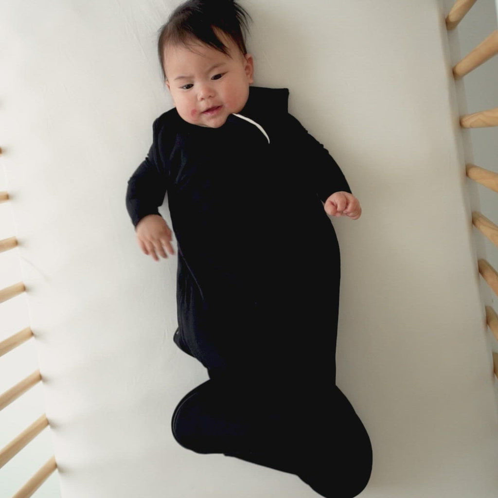 baby in crib while wearing sleep bag in midnight
