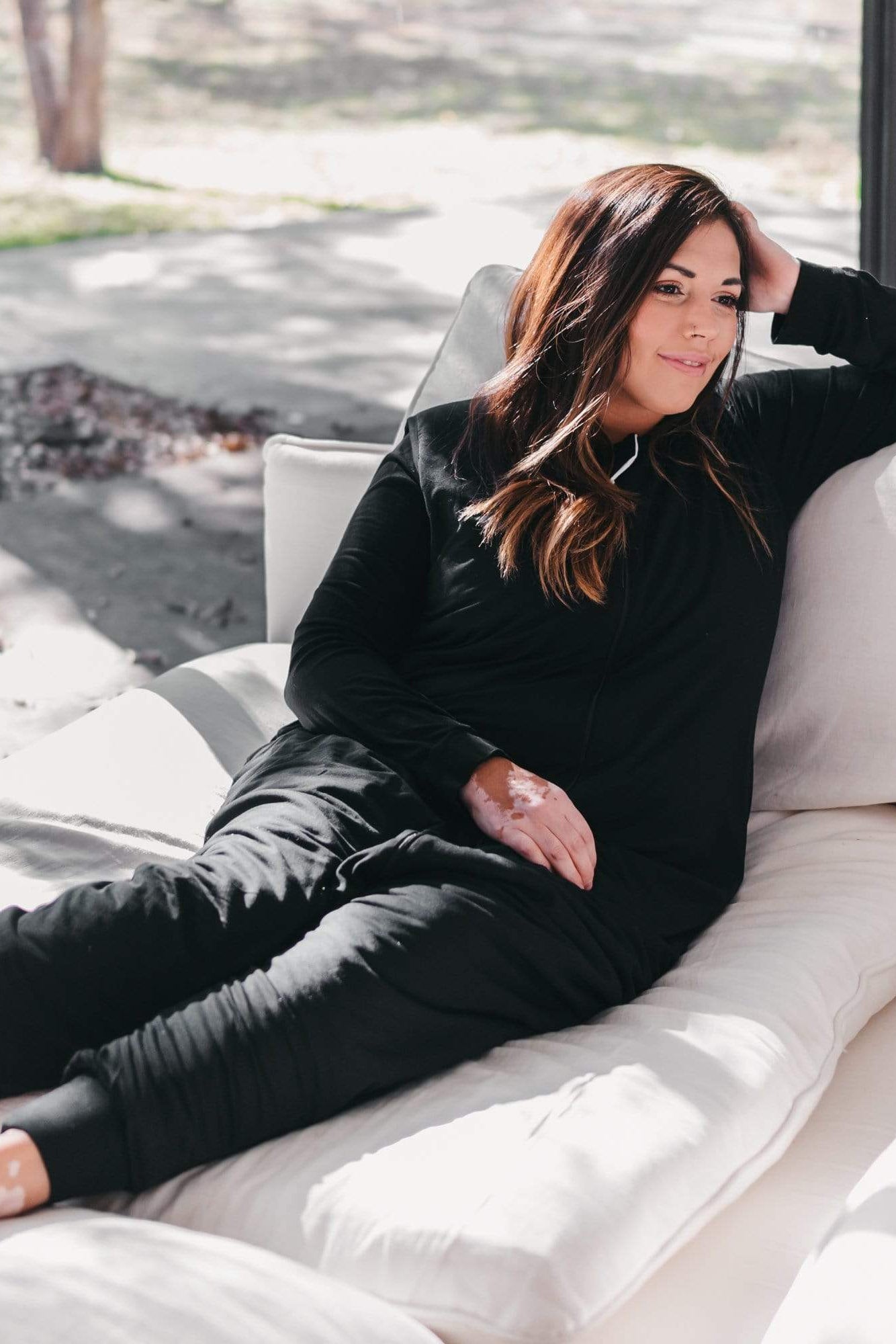 Woman lounging in Kyte Baby Adult Sleep Bag Walker in Midnight Black