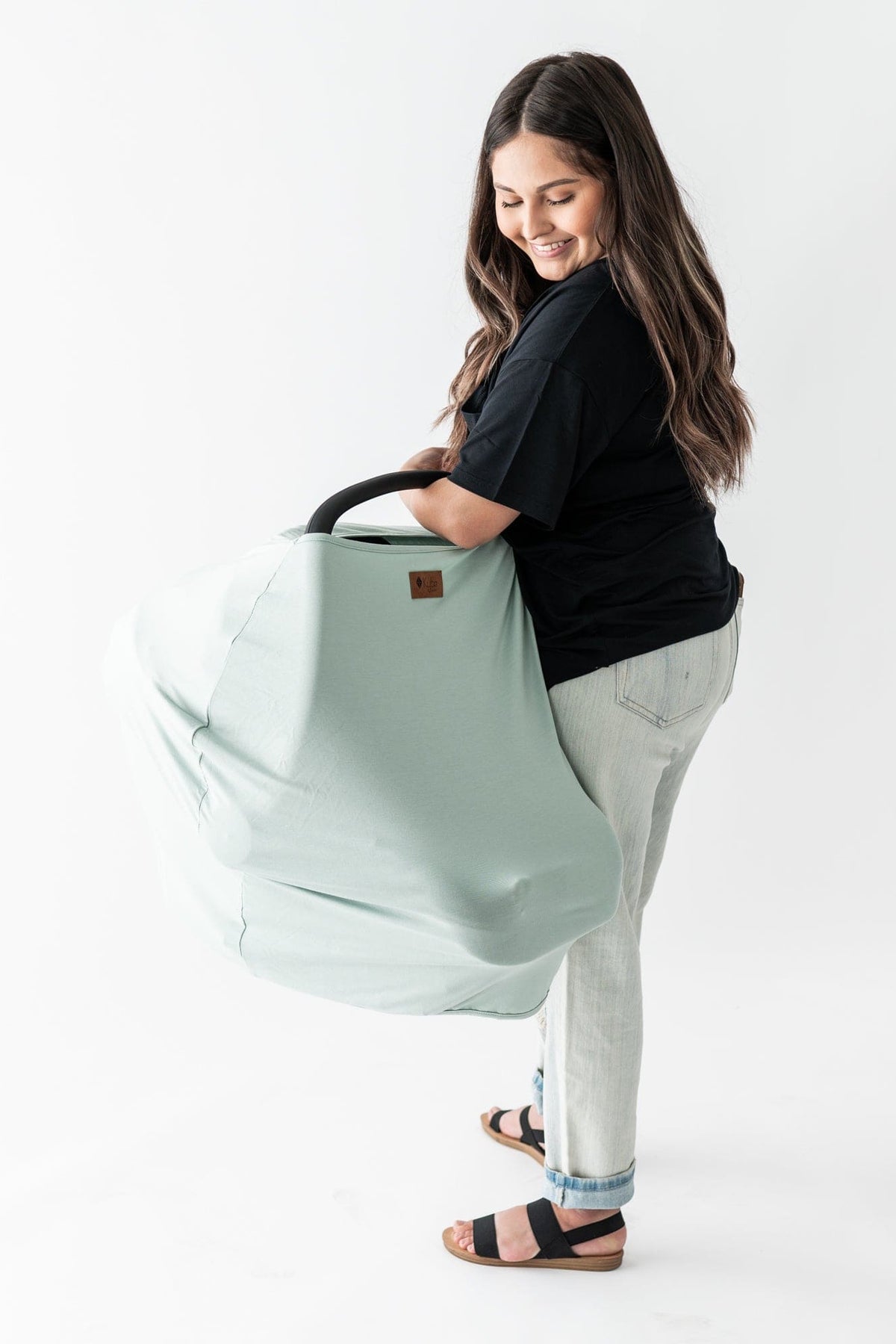 Mom carrying baby in infant carrier with Kyte Baby bamboo Car Seat Cover in Sage