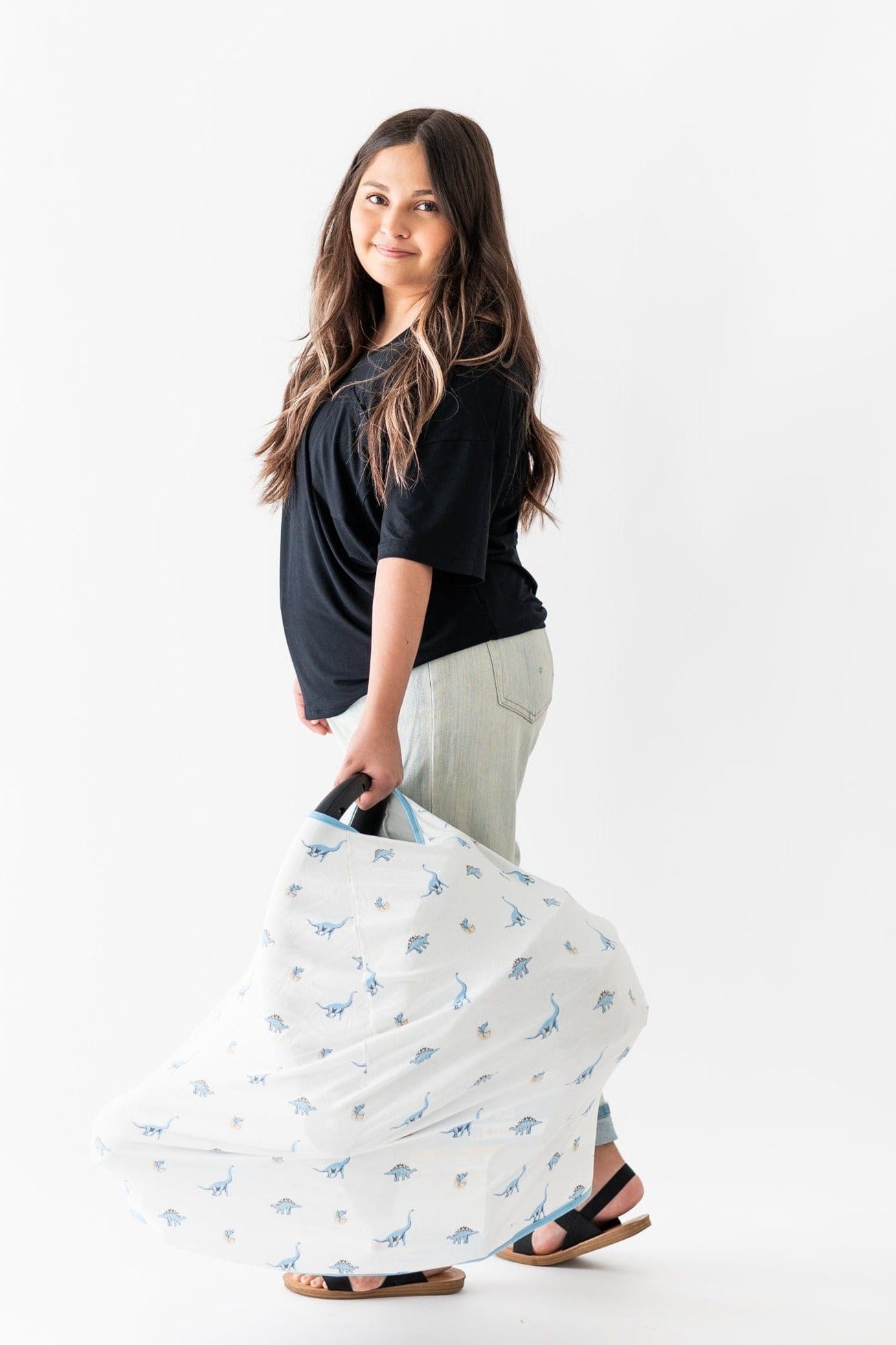 Woman carrying carseat with Kyte Baby bamboo Infant Seat Cover in Jurassic