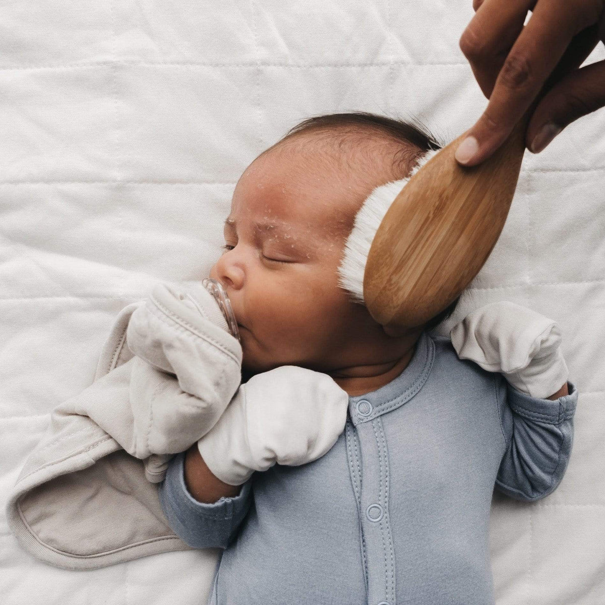 Parent using Kyte Baby brush for cradle cap on infant