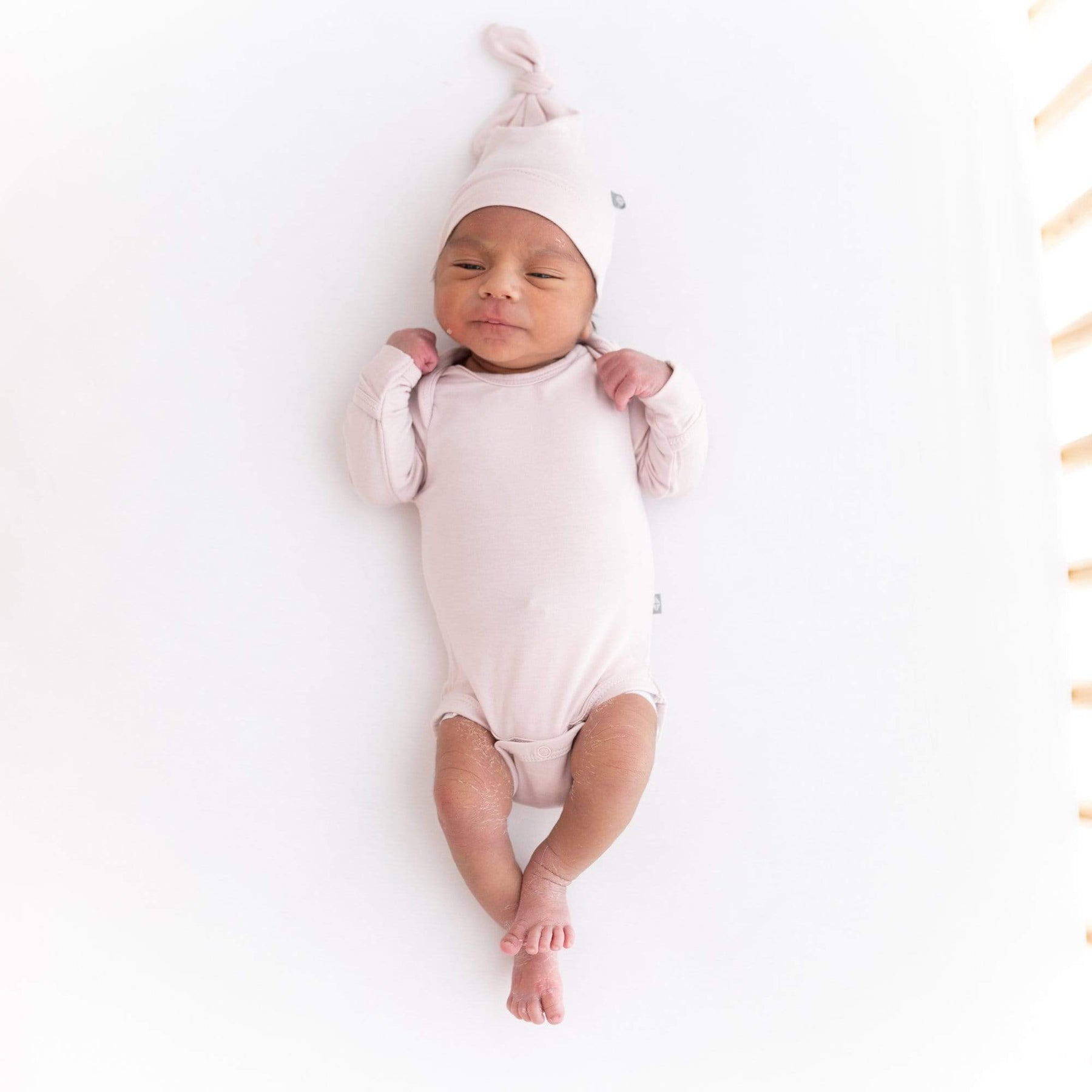 Infant wearing Kyte Baby Long Sleeve Bodysuit in Blush