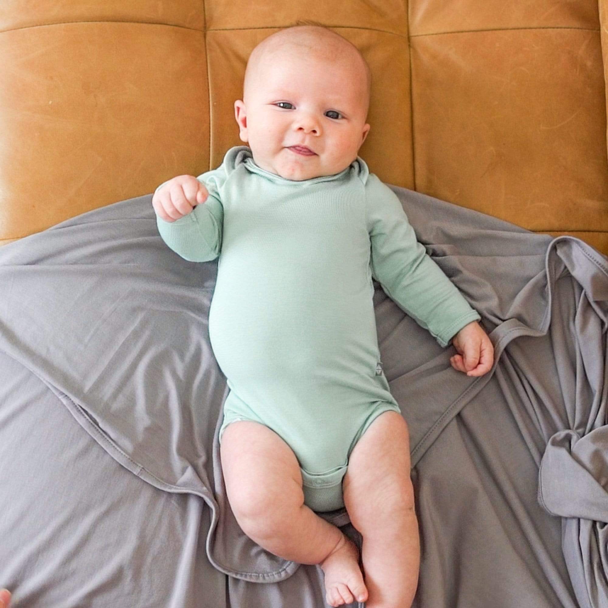 Baby wearing Kyte Baby Long Sleeve infant Bodysuit in Sage