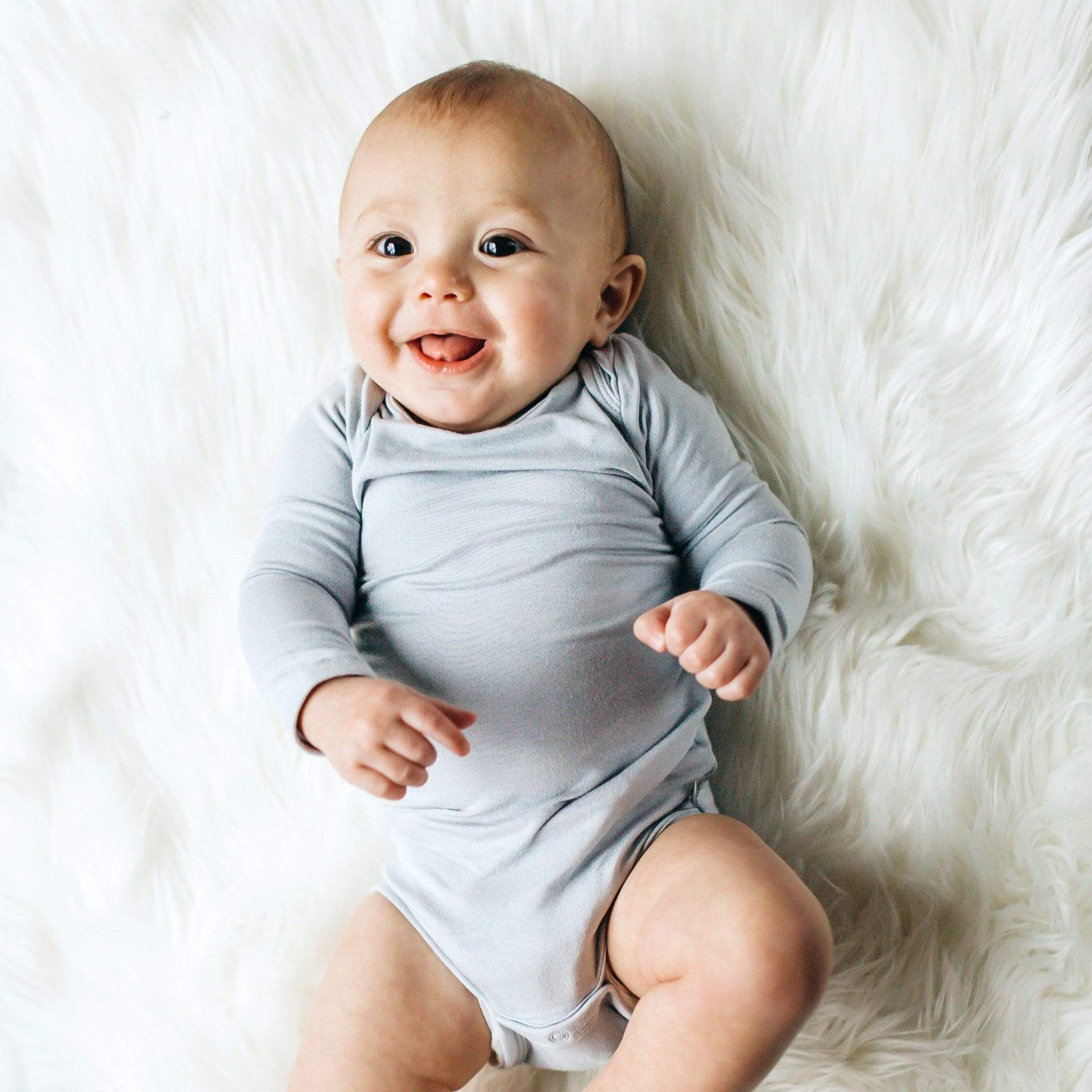 Baby wearing Kyte Baby Long Sleeve infant Bodysuit in Storm