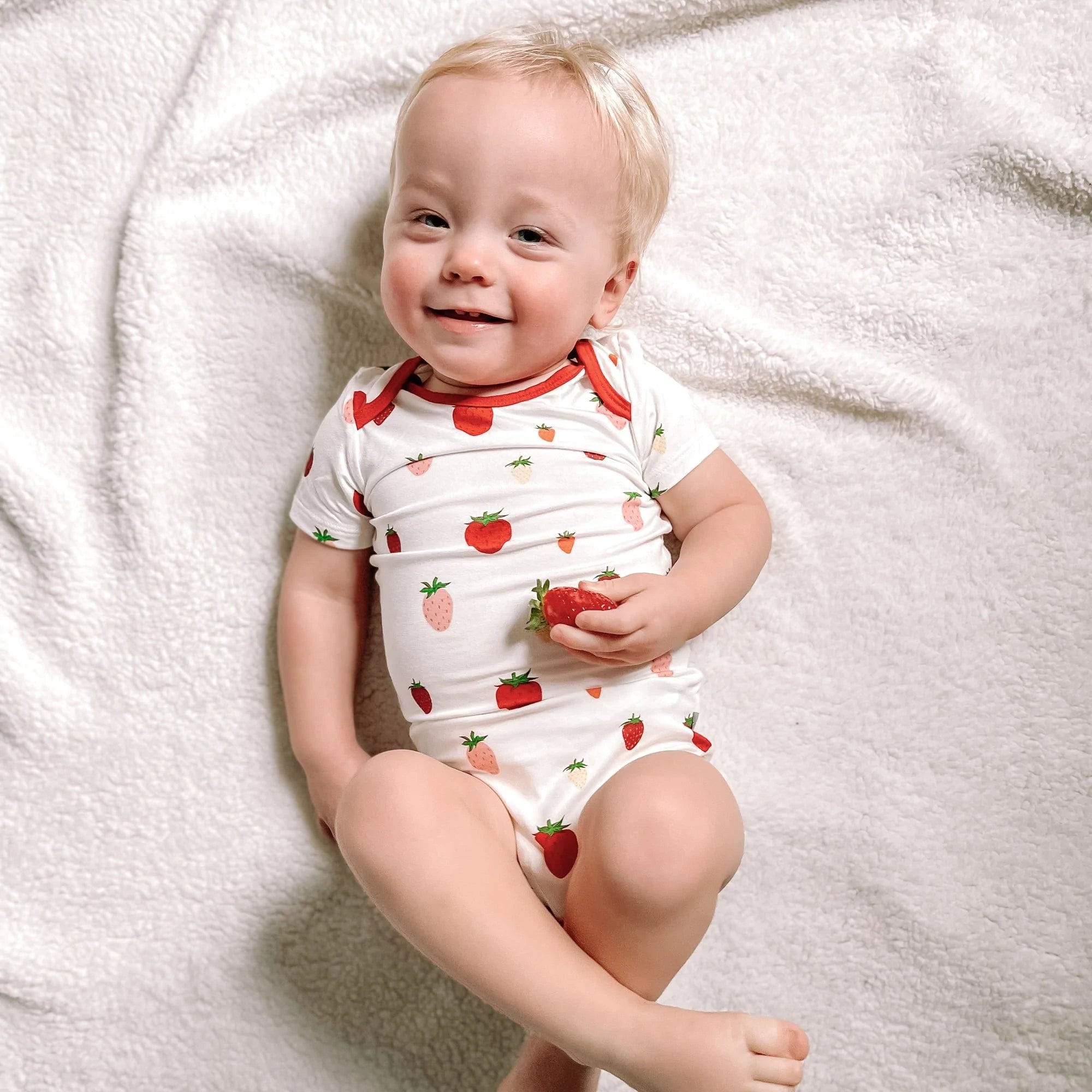 Baby wearing Kyte Baby infant Bodysuit in Strawberry