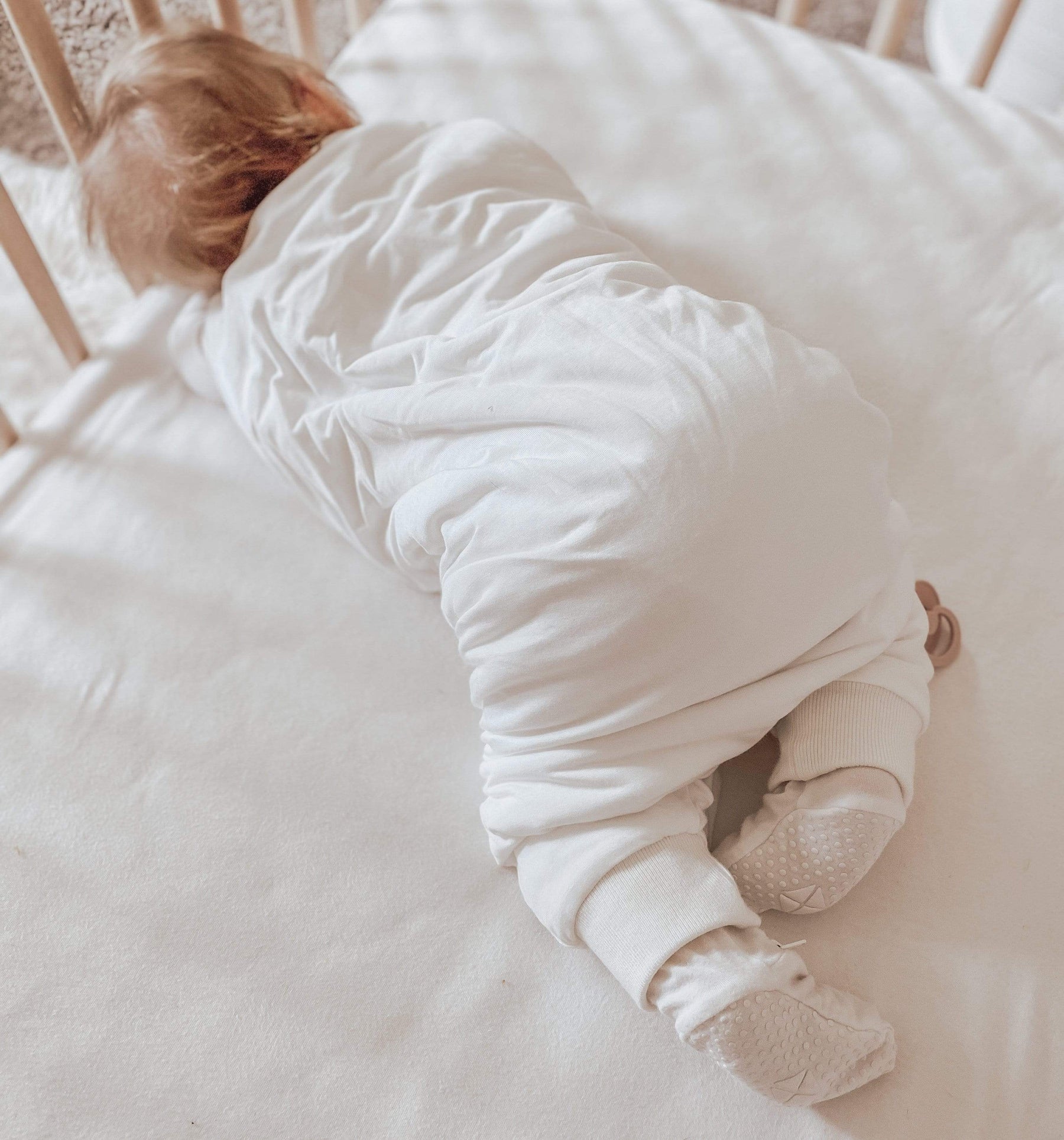 Baby wearing Kyte Baby Sleep Bag Walker in Cloud 1.0 over footie pajamas