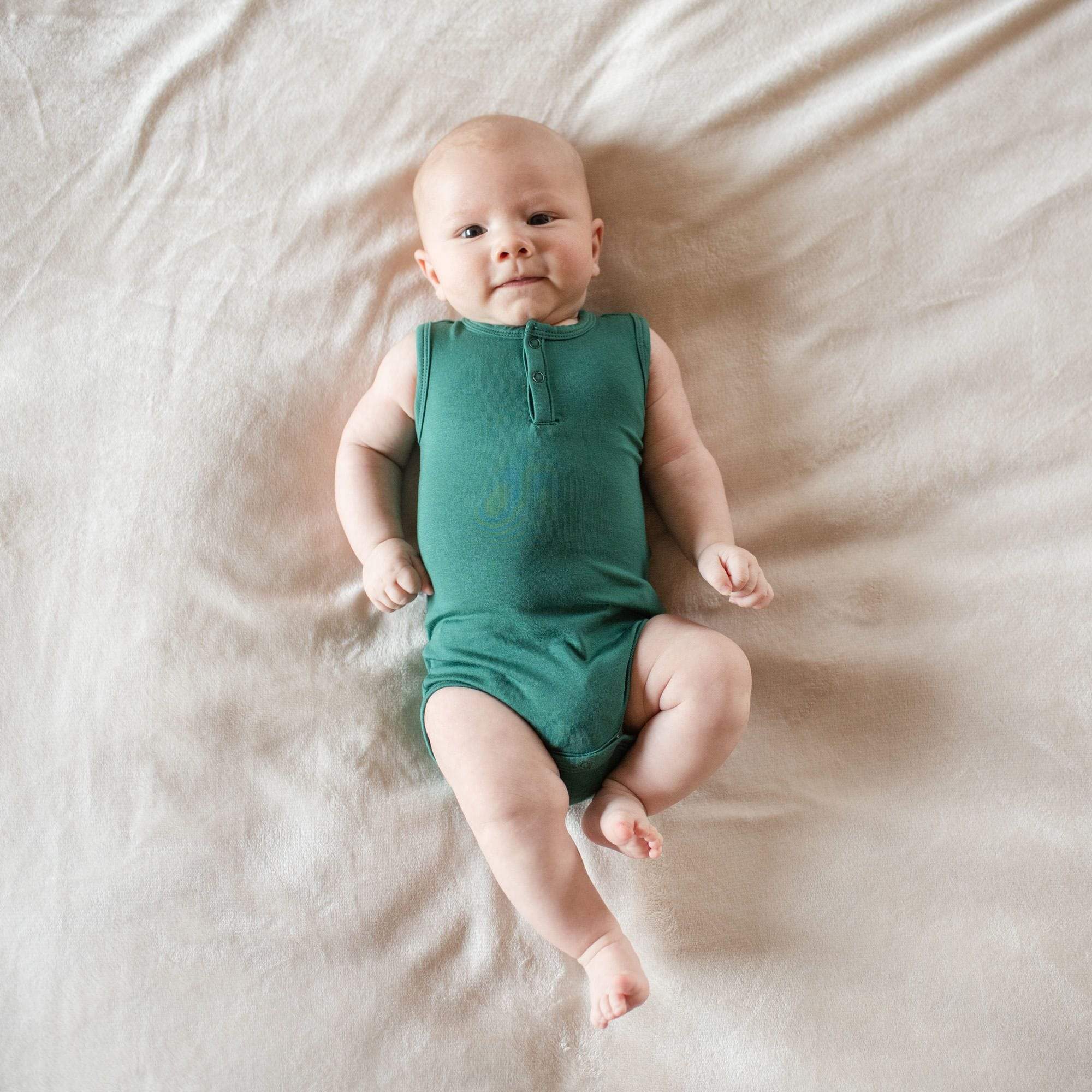 Baby wearing Kyte Baby Sleeveless infant Bodysuit in Emerald