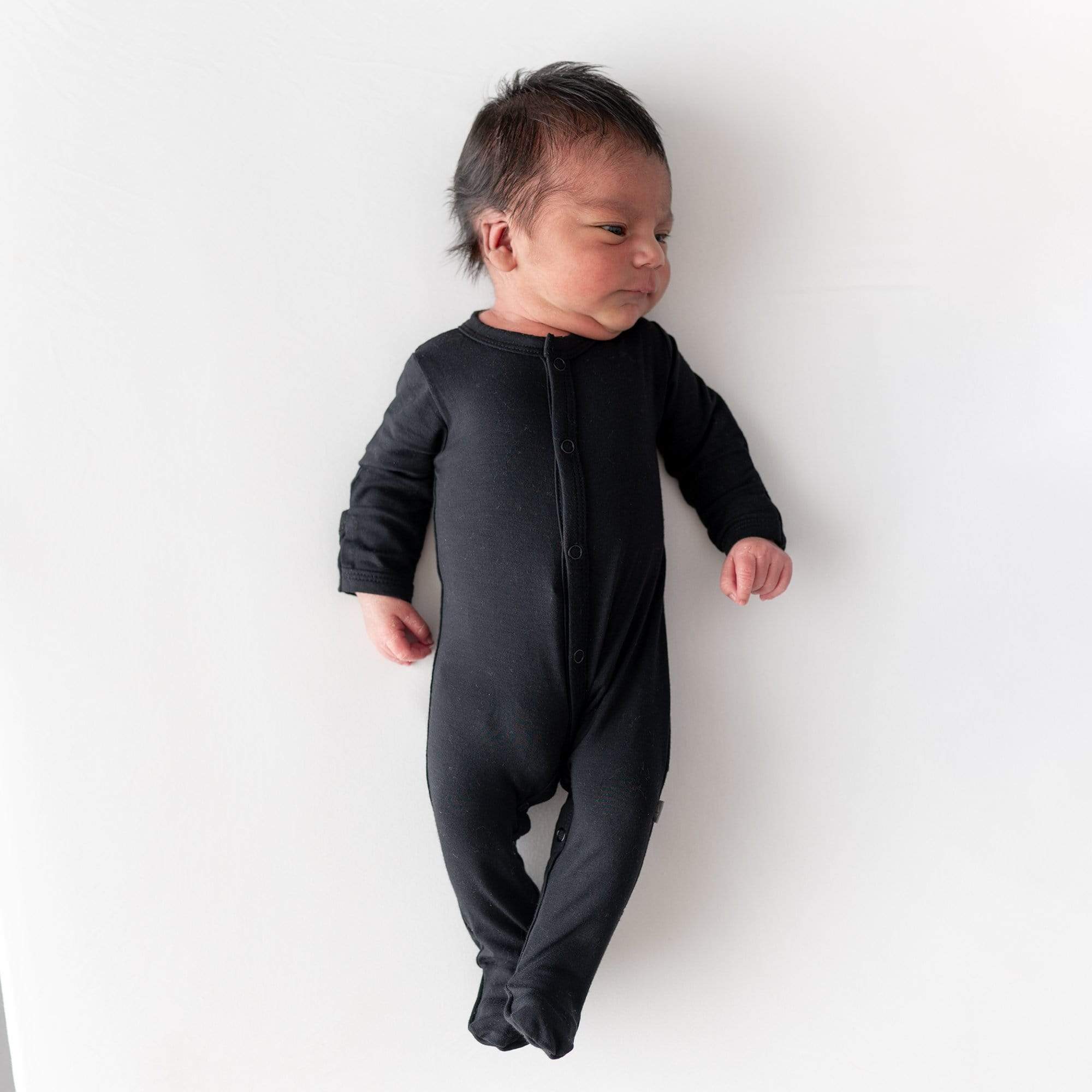 Newborn wearing Kyte Baby bamboo Snap Footie in Midnight black