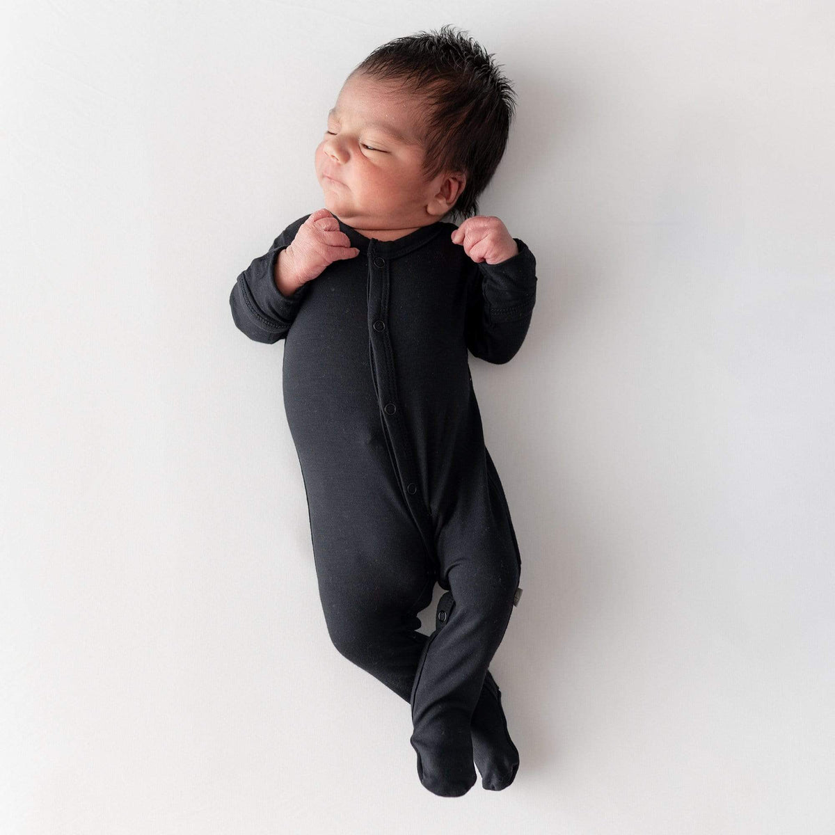 Newborn wearing Kyte Baby Footie in Midnight