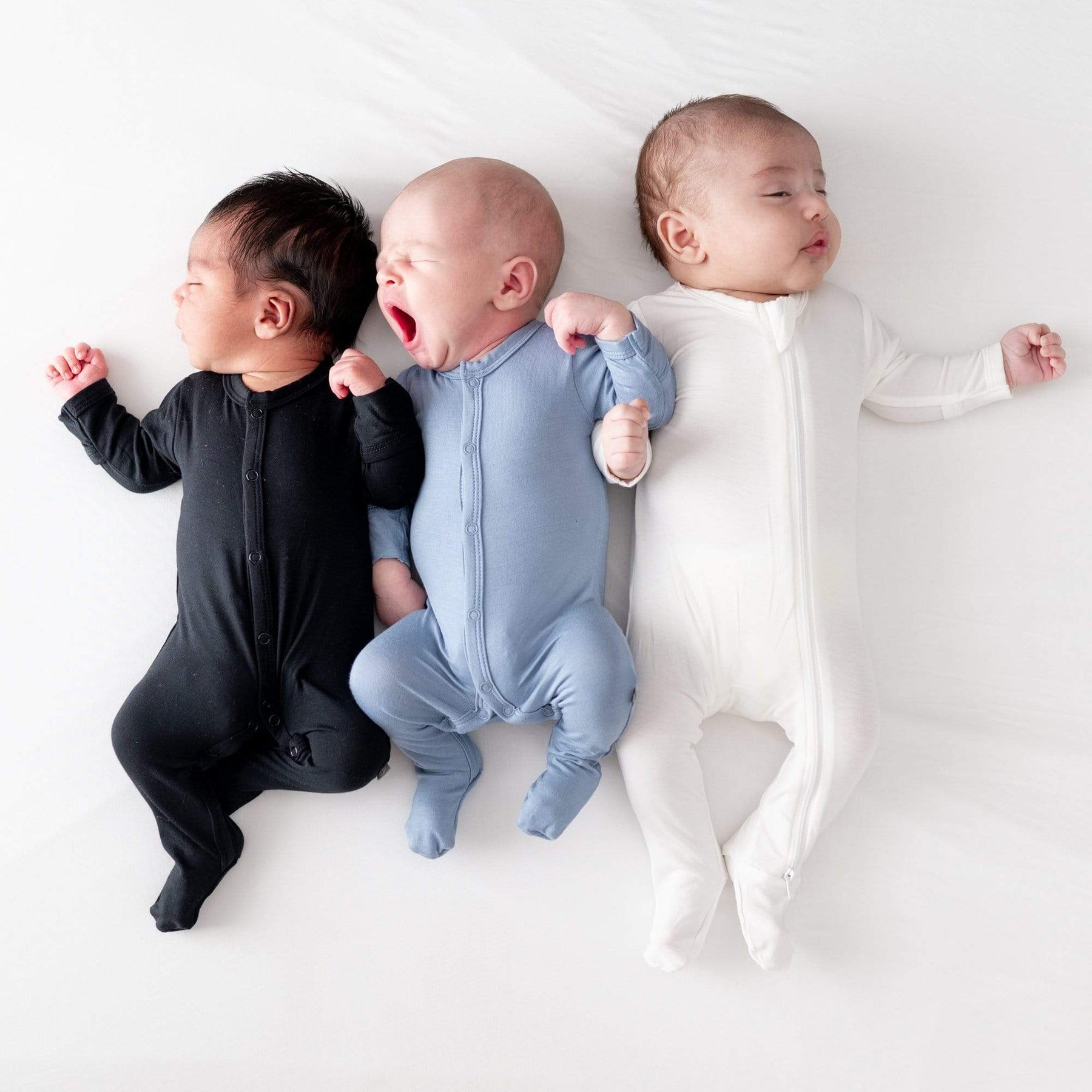 Babies wearing Kyte Baby footie pajamas in core colors