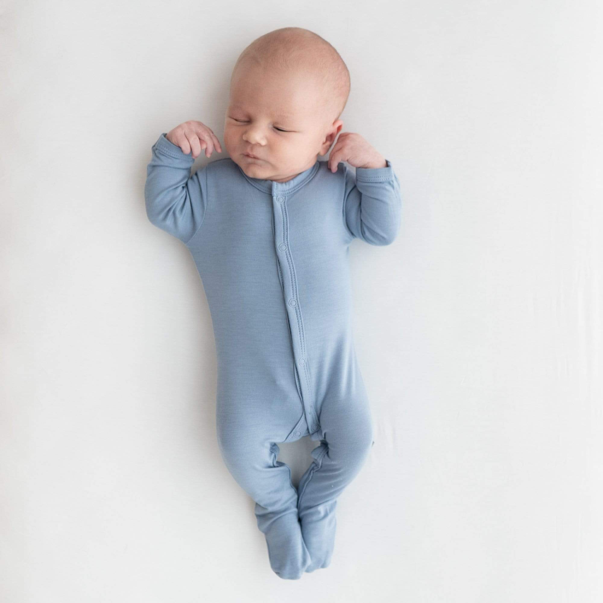 Newborn wearing Kyte Baby Footie in Slate