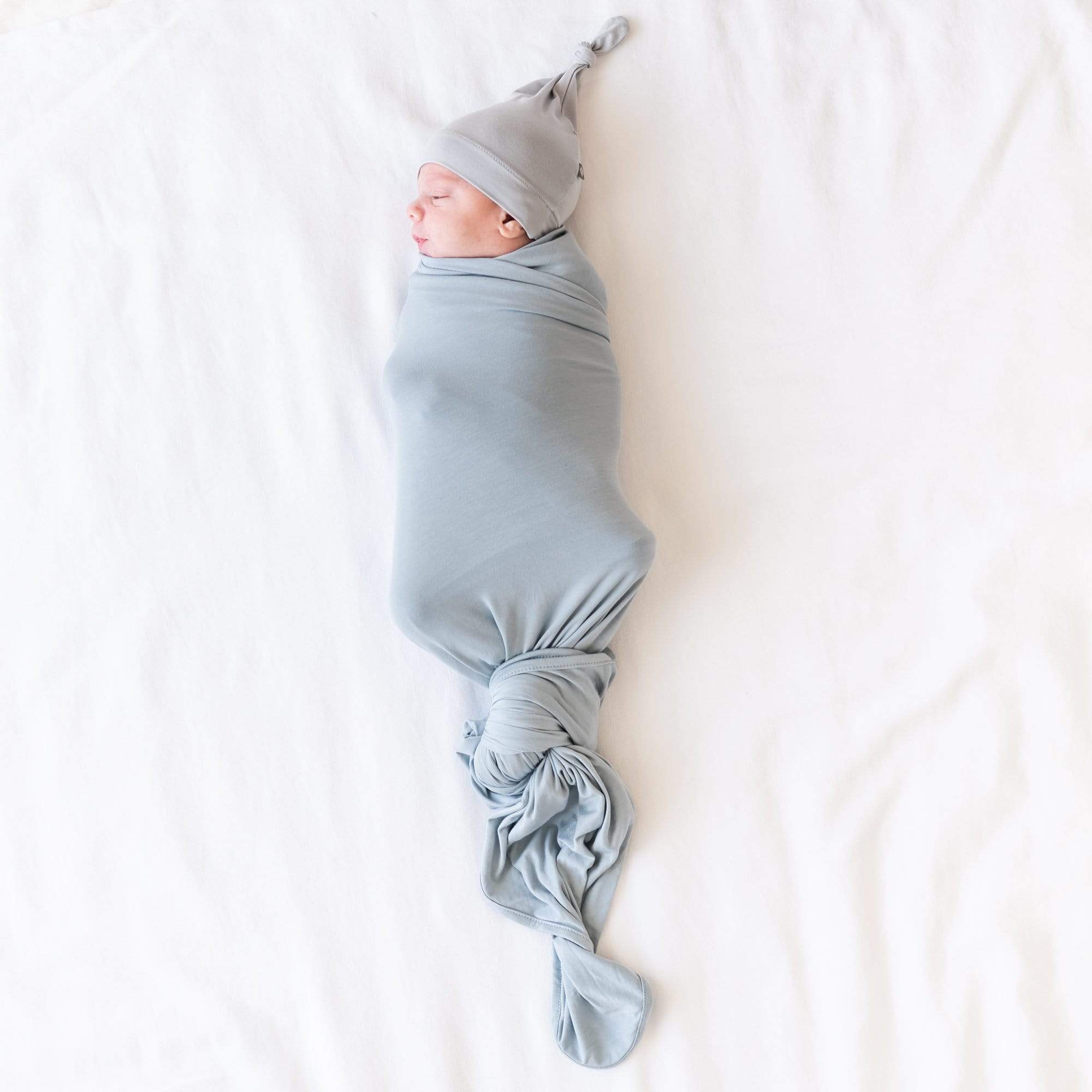 Newborn swaddled in Kyte Baby Swaddle Blanket in Fog