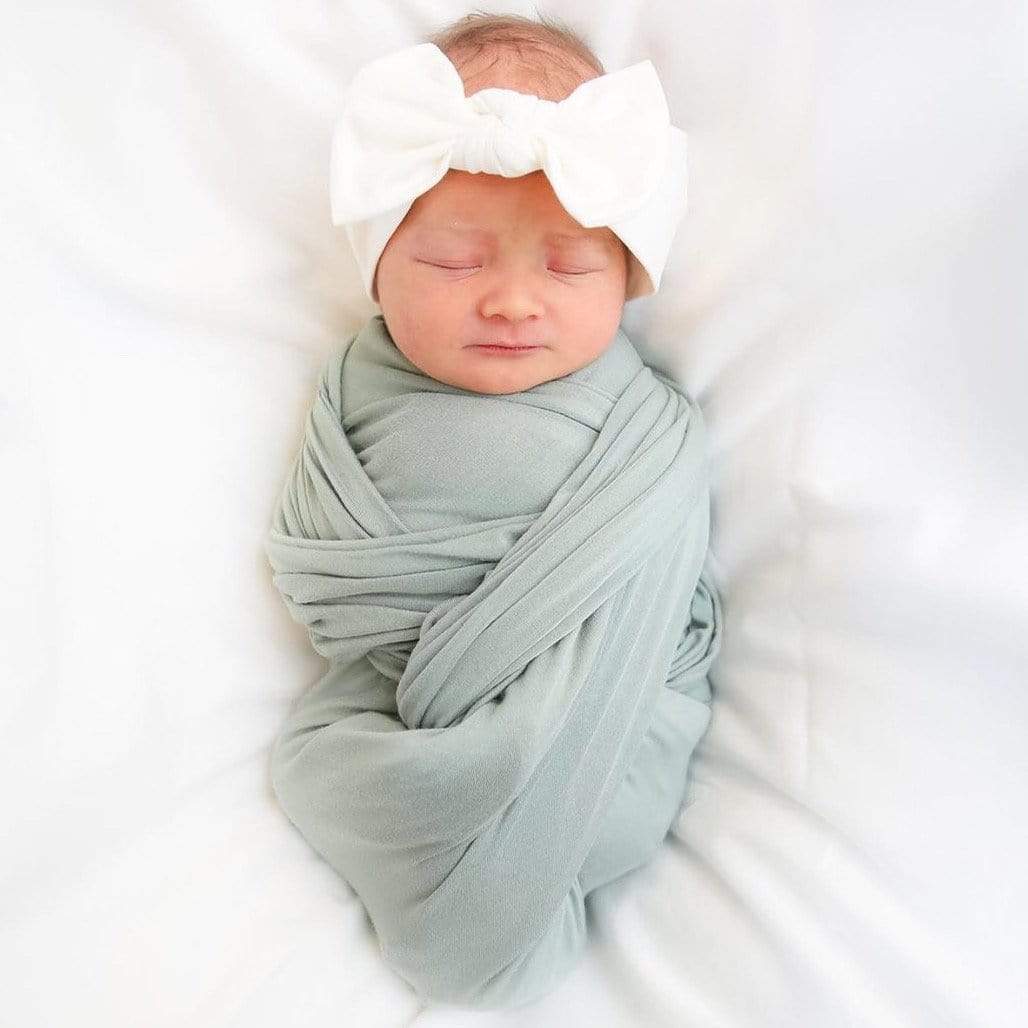Newborn swaddled in Kyte Baby Swaddle Blanket in Sage
