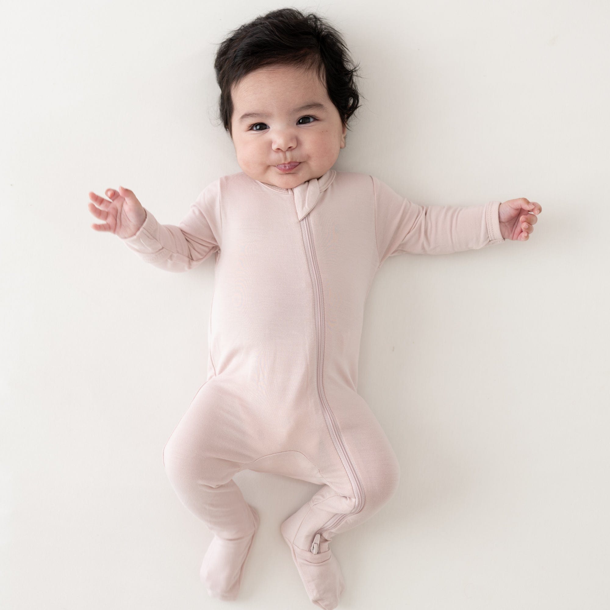 Baby wearing Kyte Baby Zippered Footie pajama in Blush pink